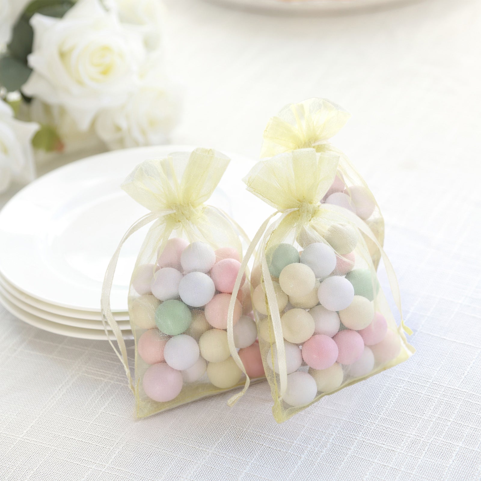 Yellow organza gift bags with pastel balls, perfect for party favors.