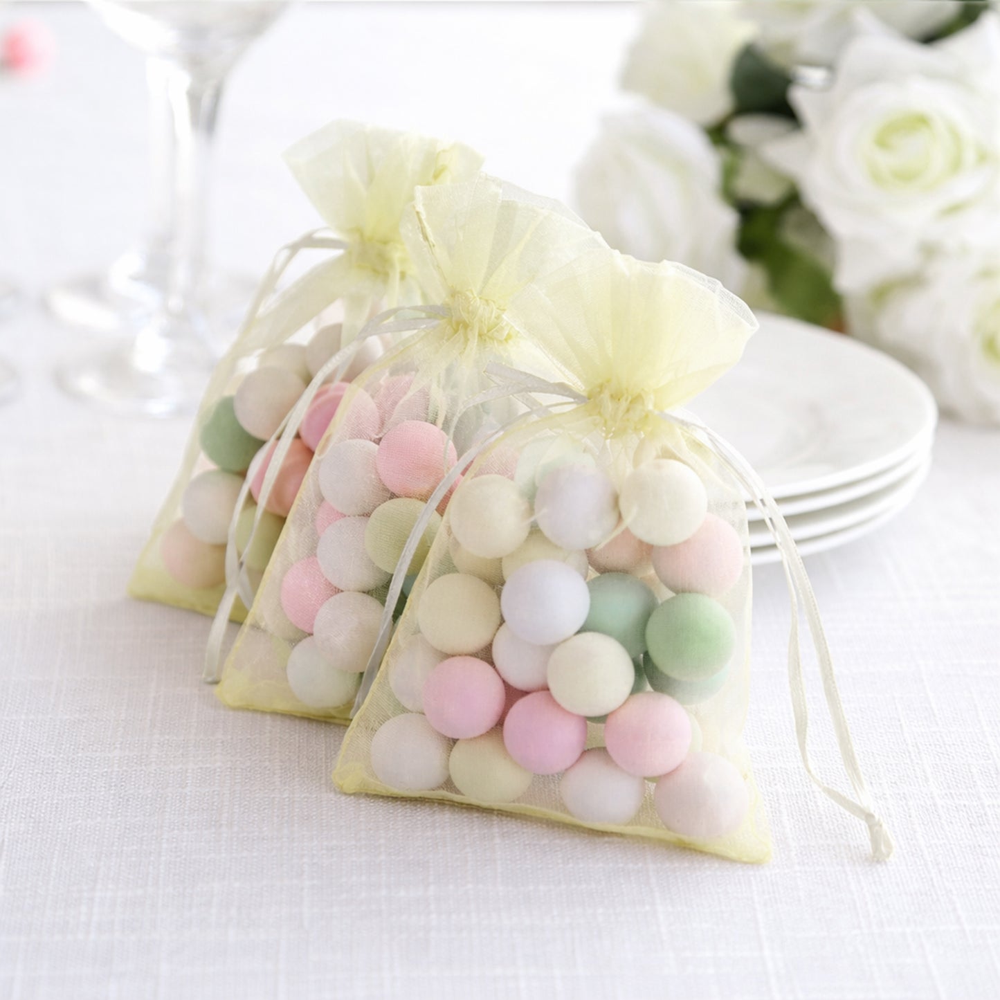 Yellow organza gift bags with drawstring filled with colorful candies.