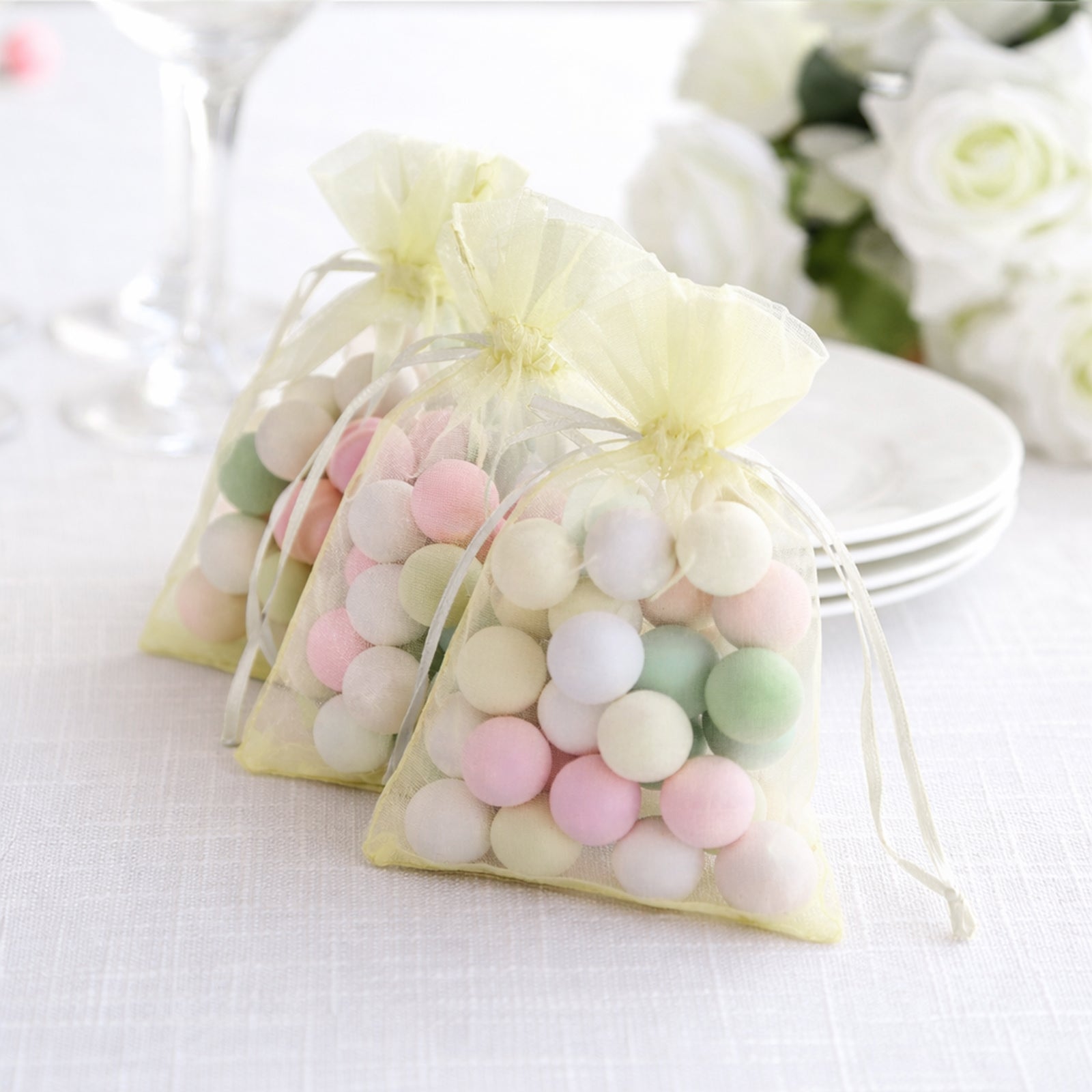 Yellow organza gift bags with drawstring filled with colorful candies.