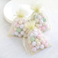 Yellow organza gift bags with drawstring filled with pastel balls.