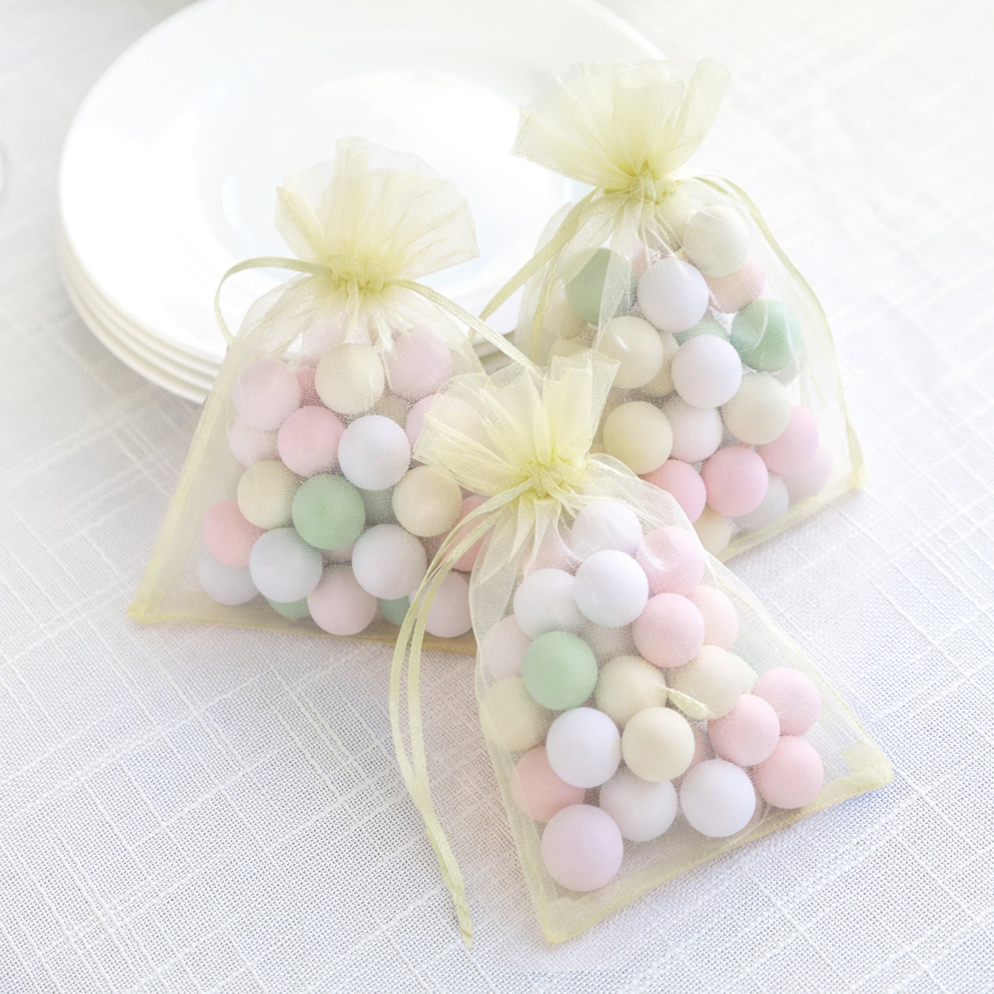 Yellow organza gift bags with drawstring filled with pastel balls.