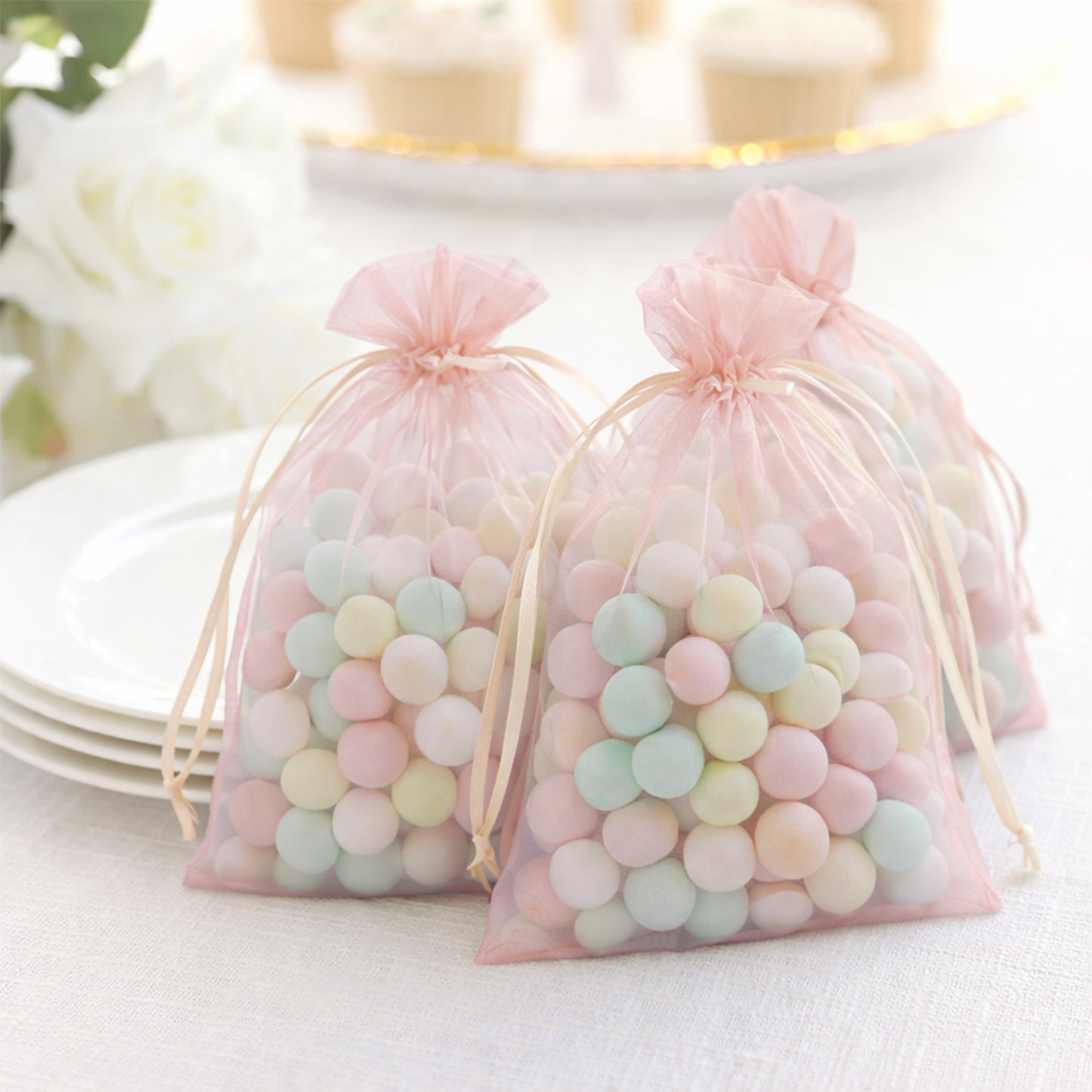 Blush organza gift bags with drawstring filled with colorful candies.