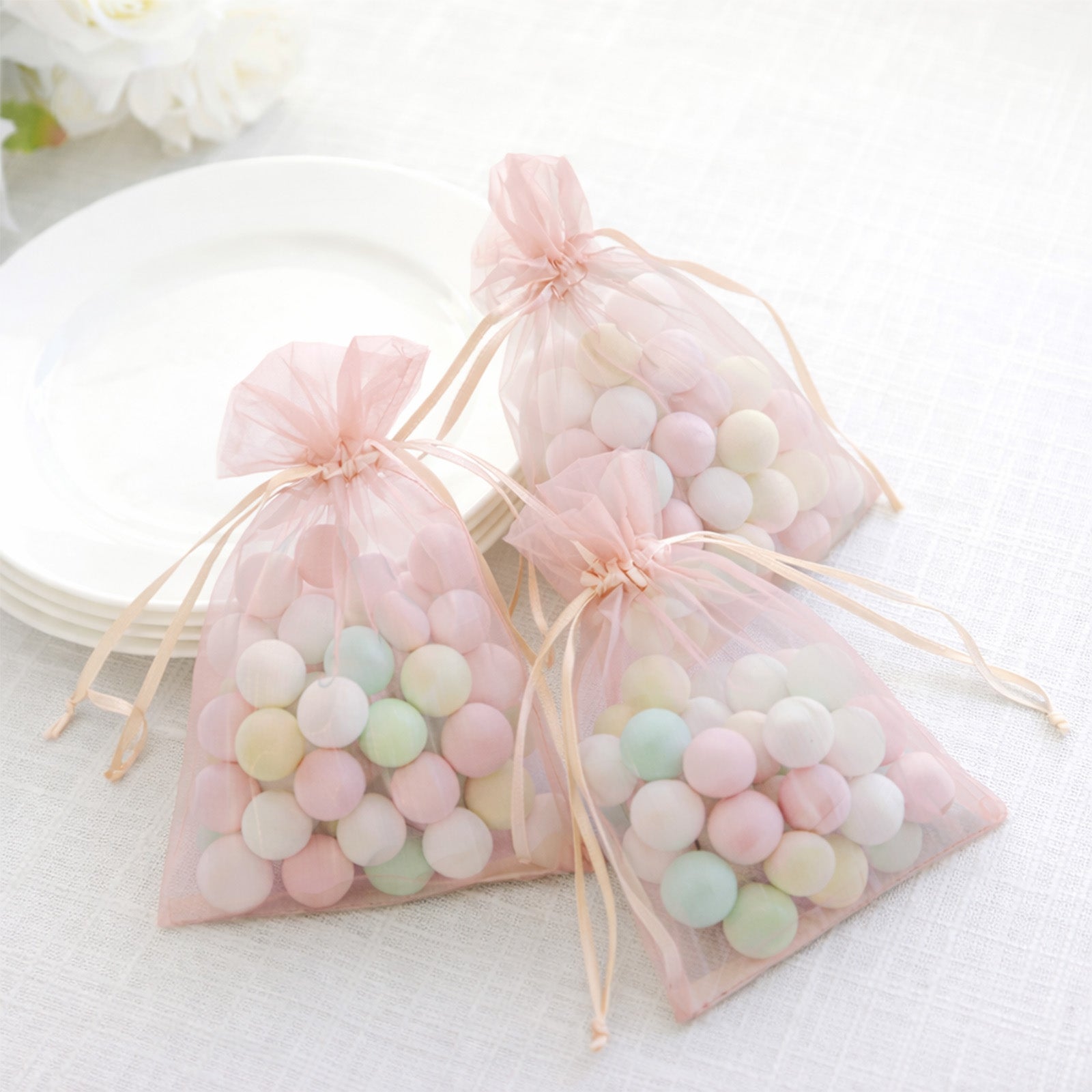 Blush organza gift bags filled with colorful candies, ideal for party favors.