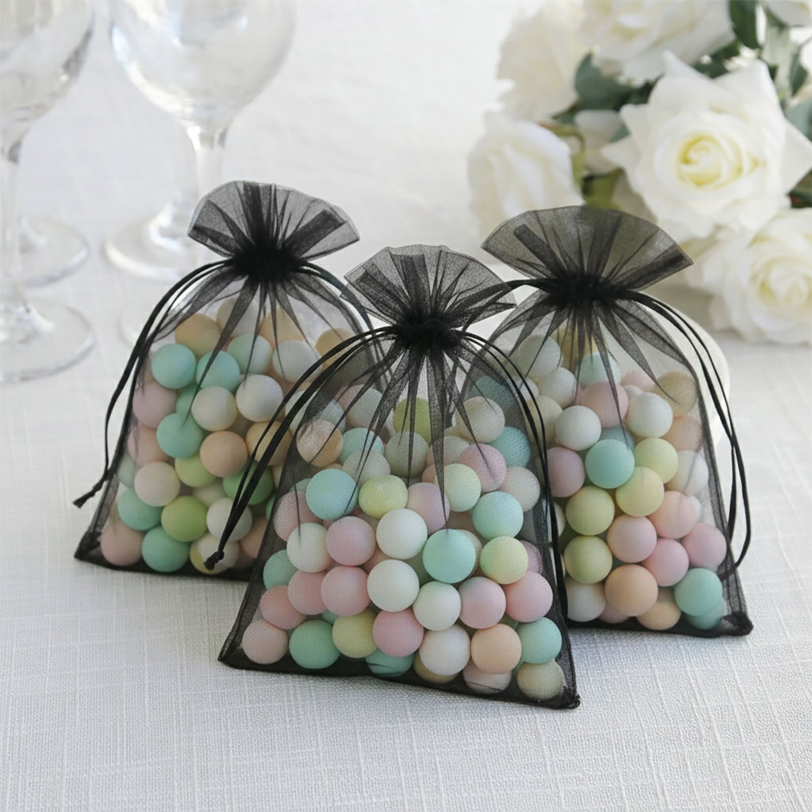 Black organza gift bags filled with pastel candies. Perfect for weddings and parties.