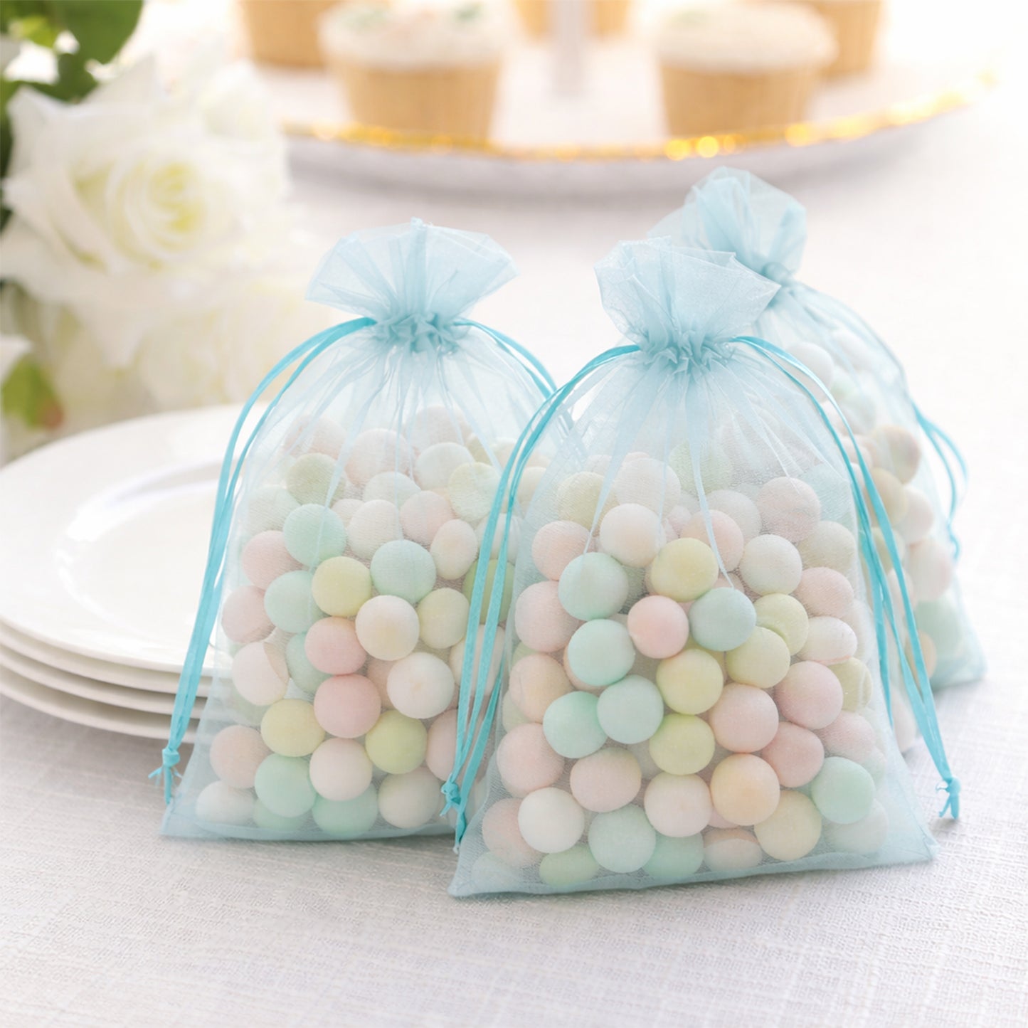 Light blue organza gift bags filled with colorful candies.