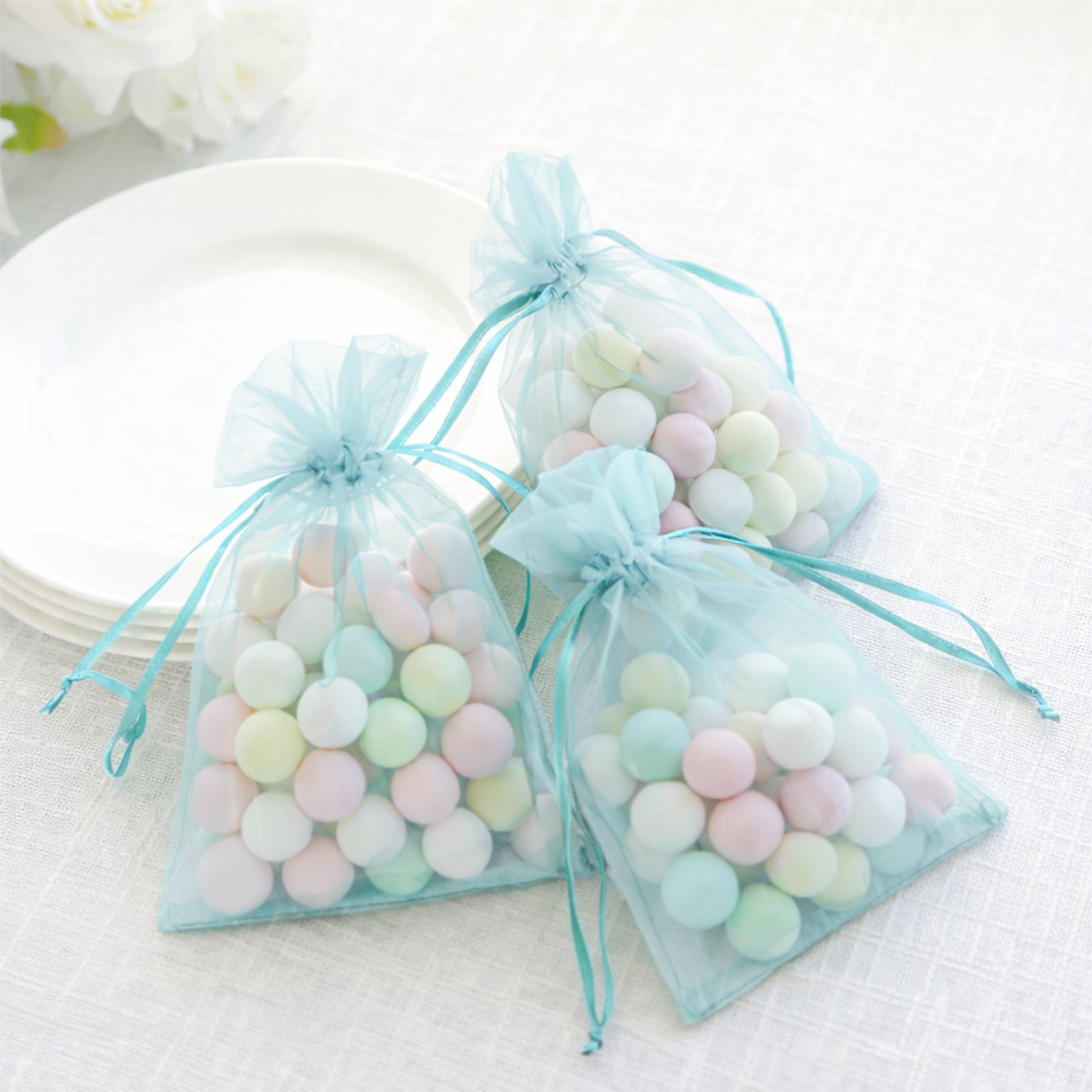 Light blue organza gift bags filled with pastel candies, perfect for weddings.