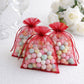 Burgundy organza gift bags filled with colorful candies for wedding favors.