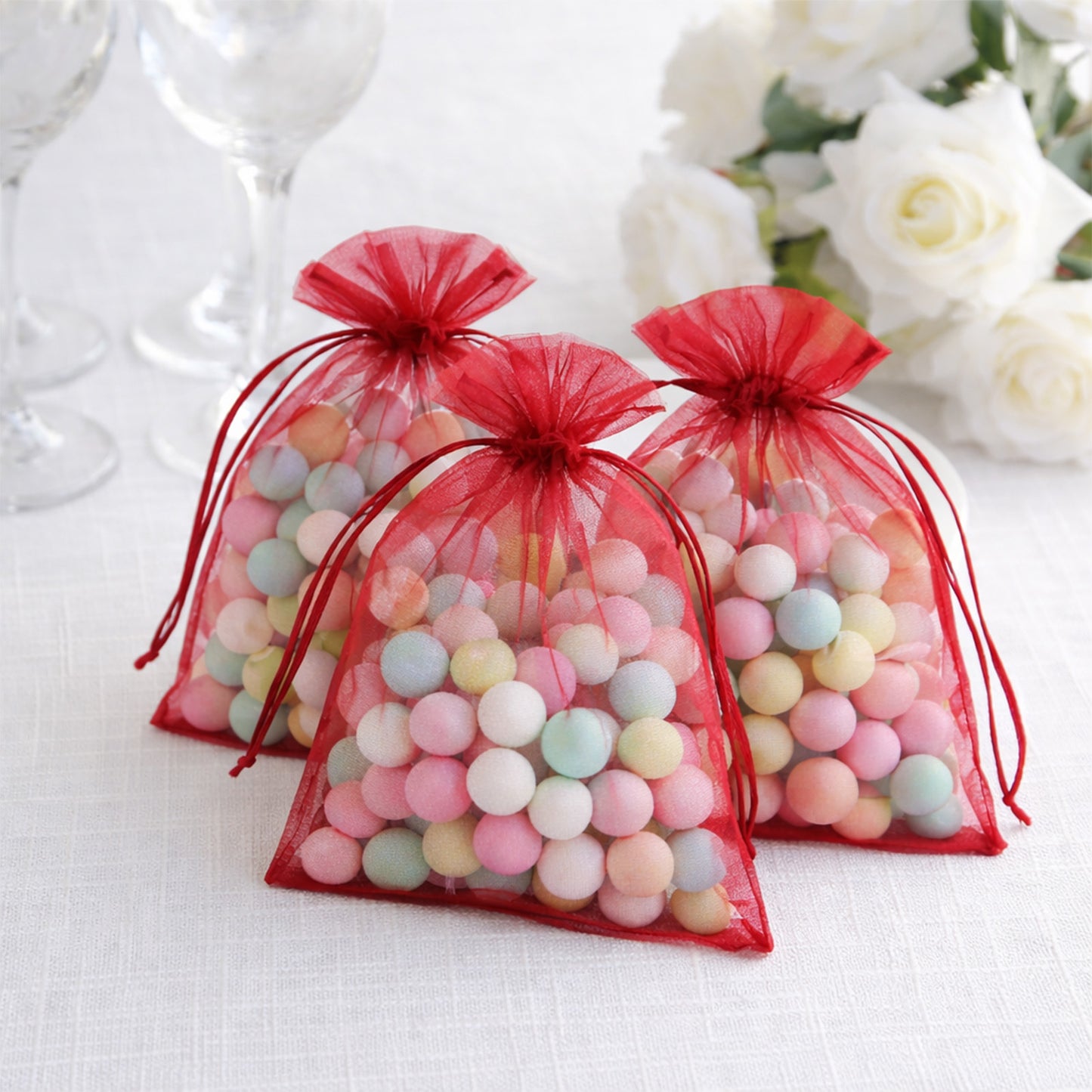 Burgundy organza gift bags filled with colorful candies for wedding favors.