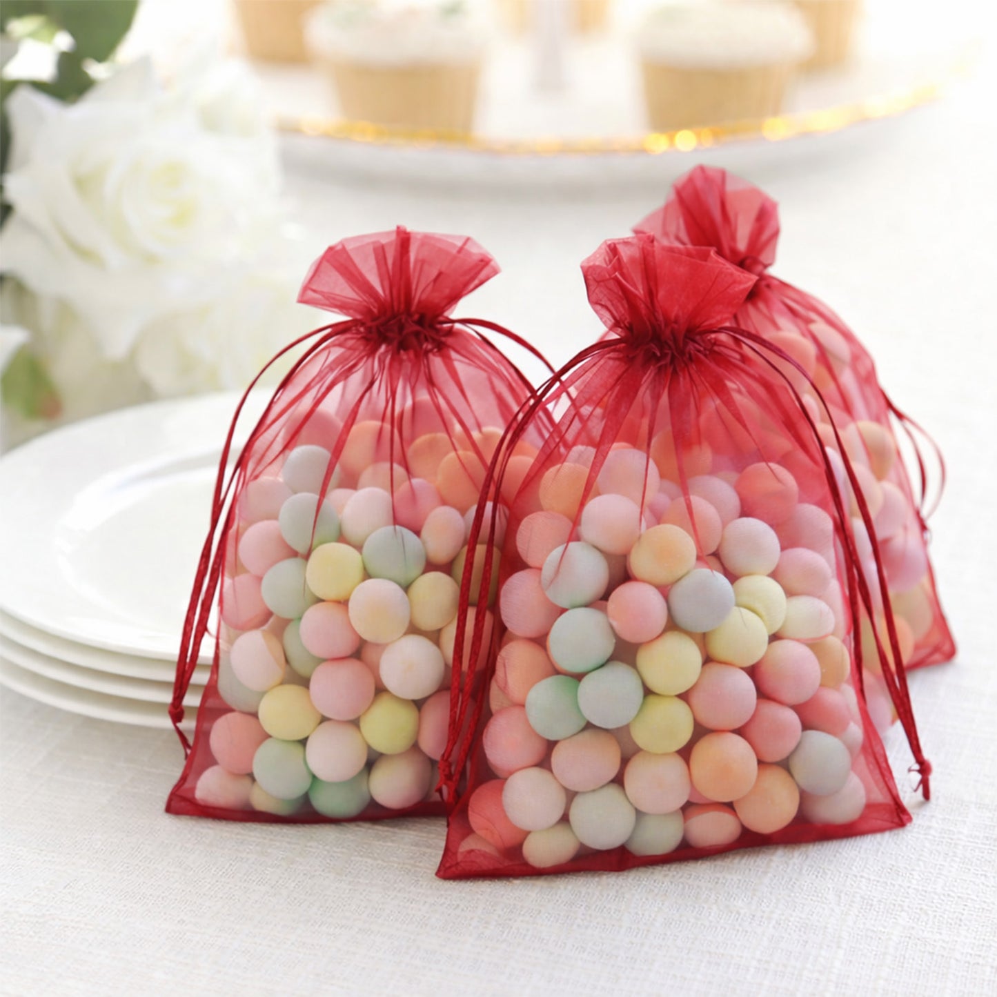 Burgundy organza gift bags filled with colorful candies.