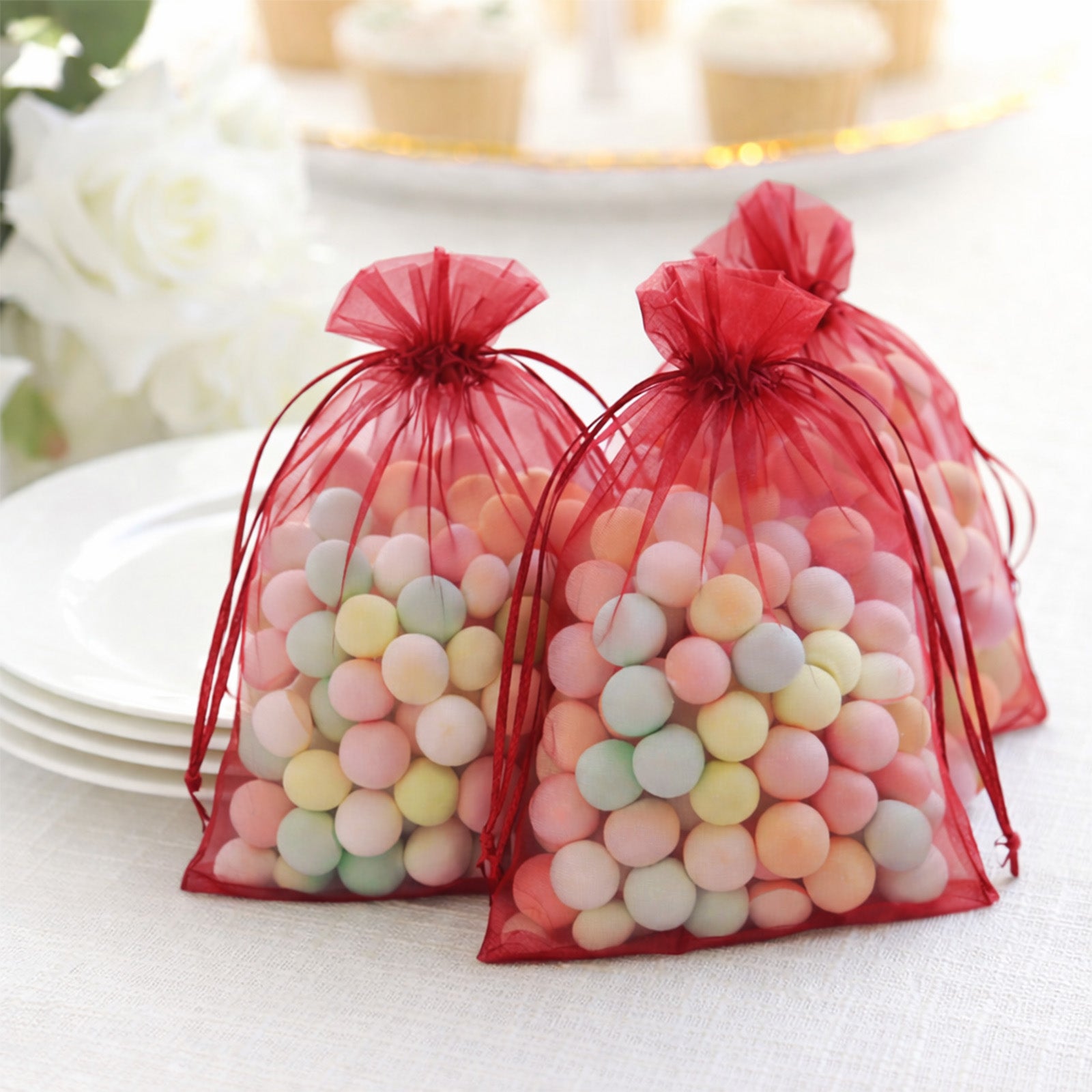 Burgundy organza gift bags filled with colorful candies.