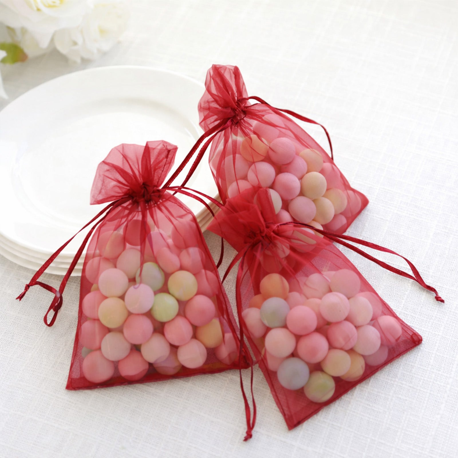 Burgundy organza gift bags with drawstring for wedding favors.