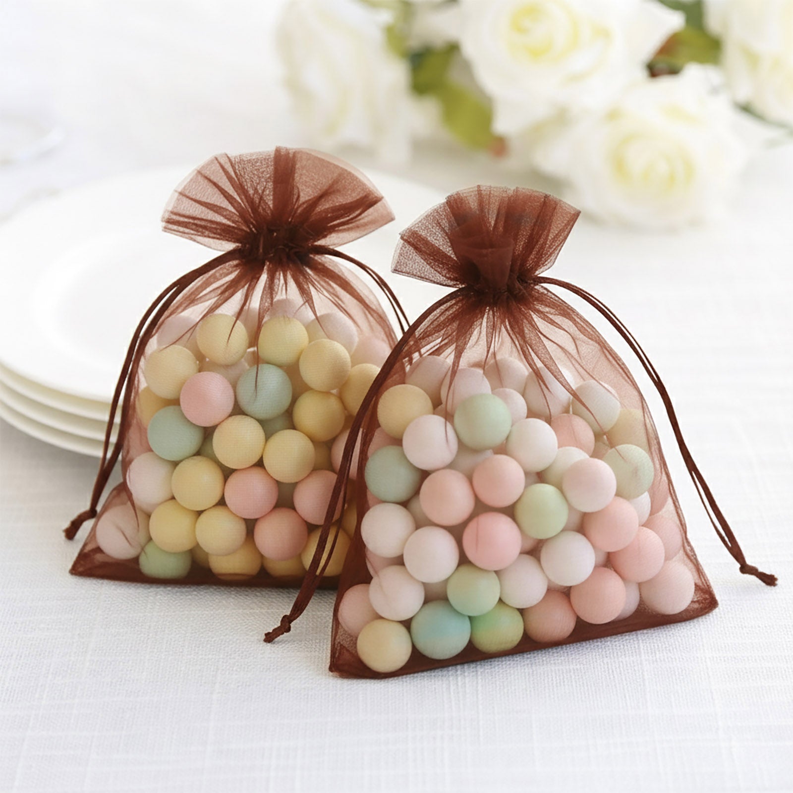 Brown chocolate organza gift bags with drawstring, filled with pastel candies.