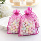 Fuchsia organza gift bags filled with pastel candies, perfect for party favors.