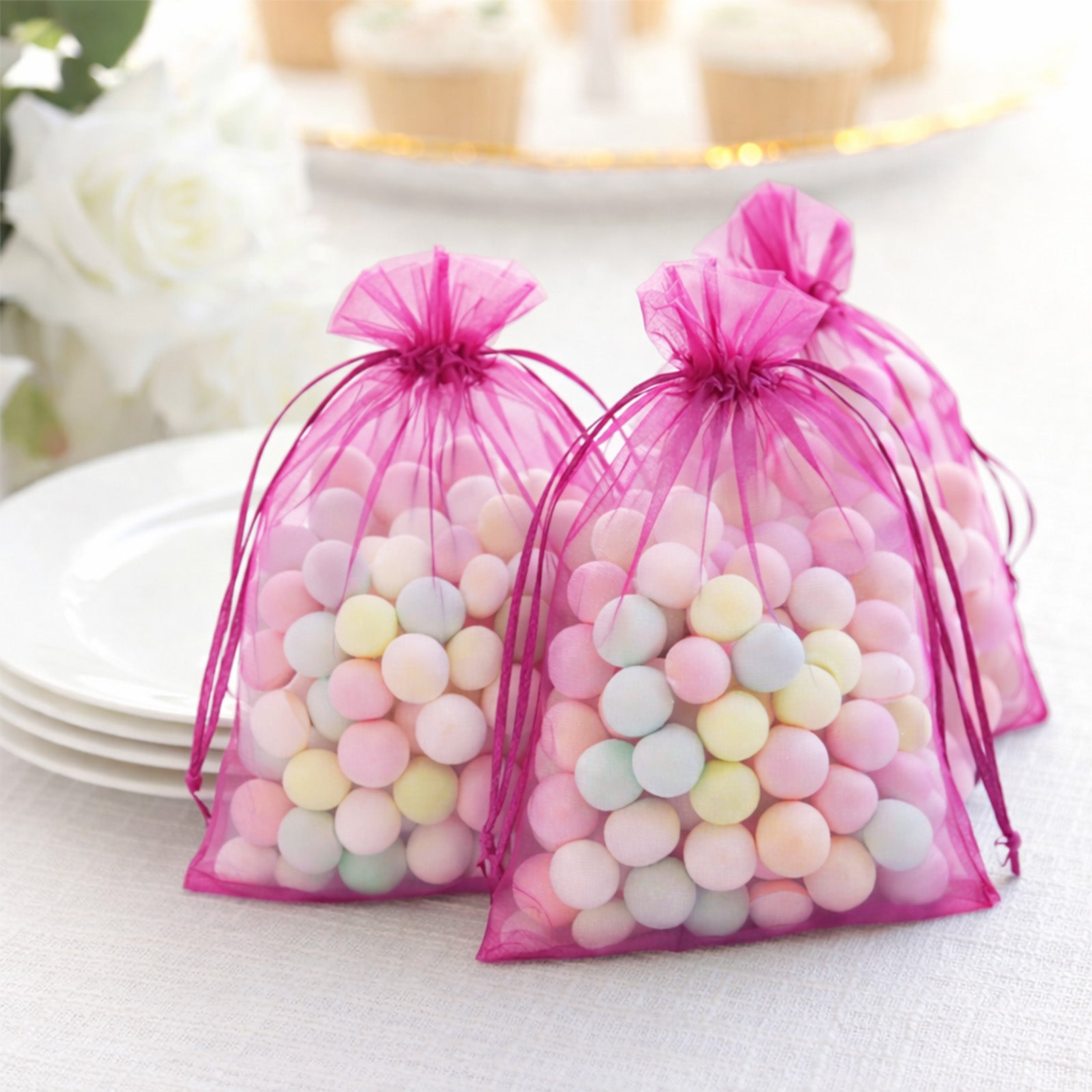 Fuchsia organza gift bags filled with pastel candies, perfect for party favors.