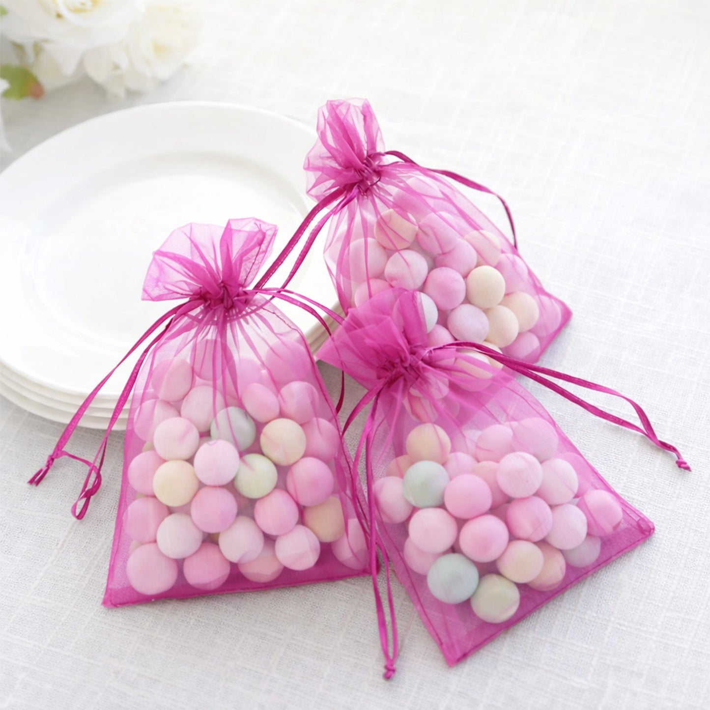Fuchsia organza gift bags with drawstring, ideal for wedding party favors.