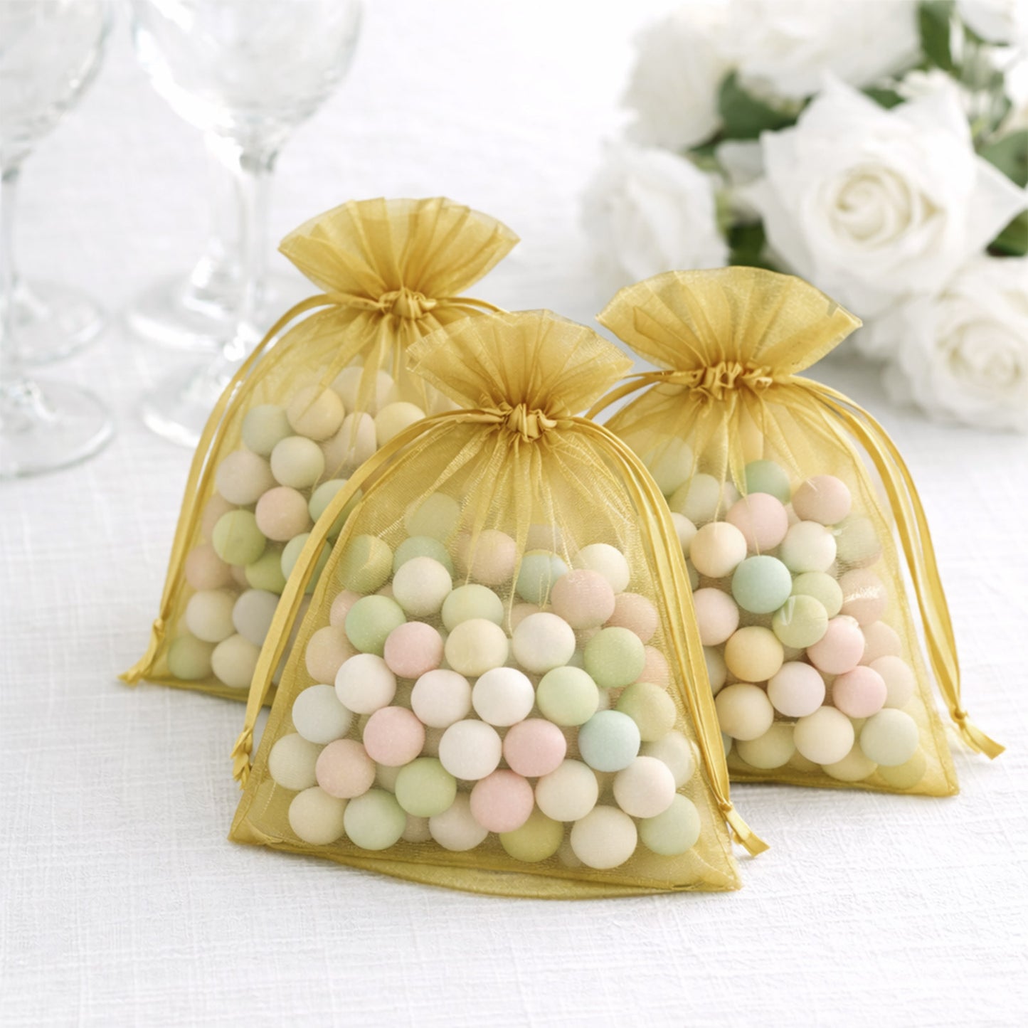 Gold organza gift bags filled with colorful treats, perfect for events.