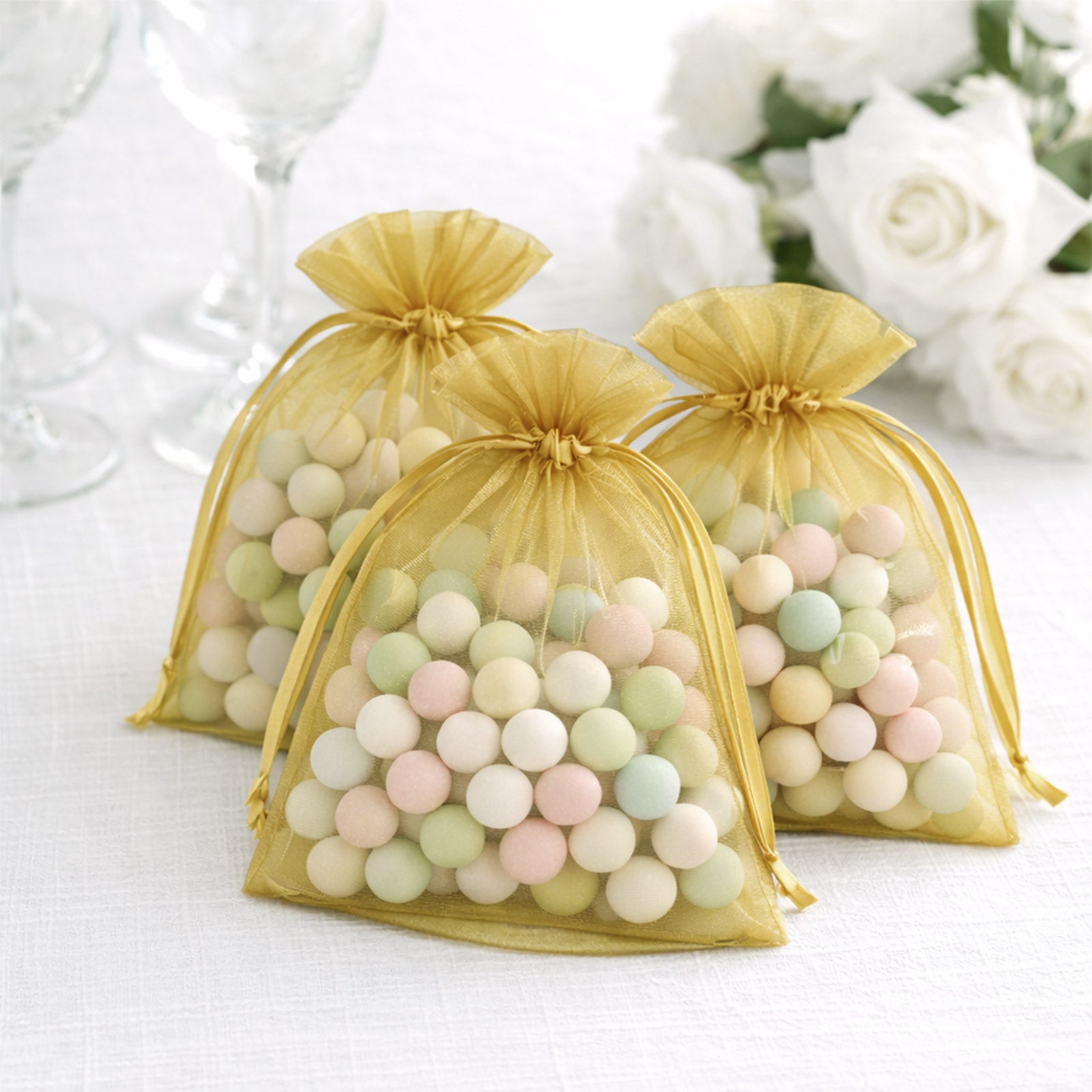 Gold organza gift bags filled with colorful treats, perfect for events.
