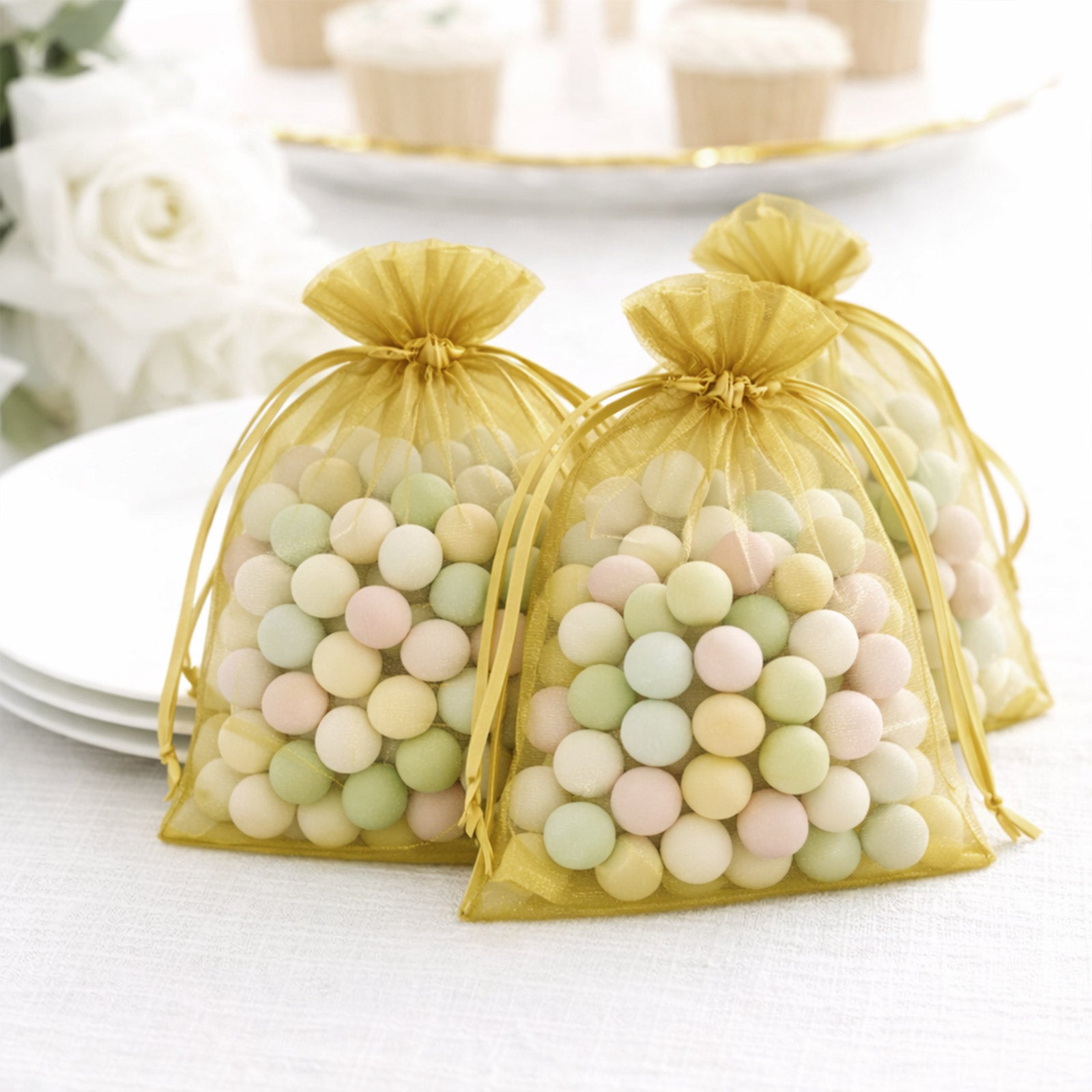 Gold organza gift bags filled with pastel candies, perfect for party favors.
