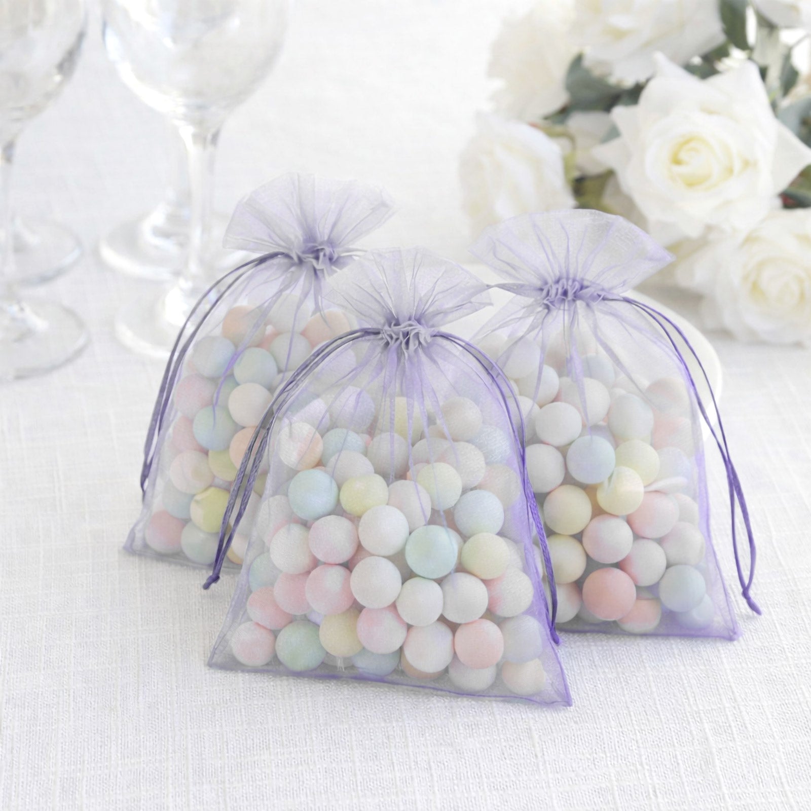 Lavender organza gift bags filled with pastel candies, perfect for party favors.