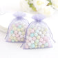 Lavender organza gift bags filled with pastel candies, perfect for wedding favors.