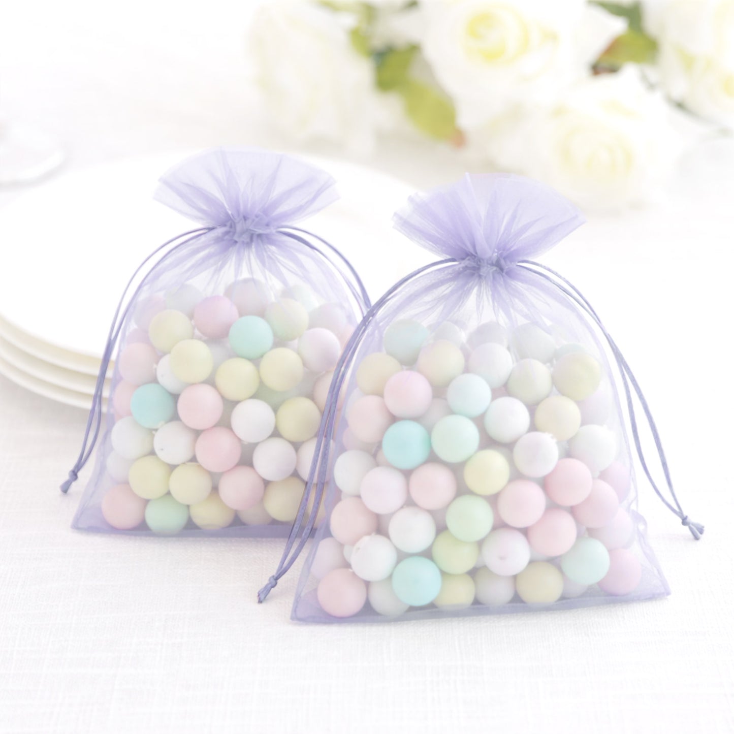 Lavender organza gift bags filled with pastel candies, perfect for wedding favors.