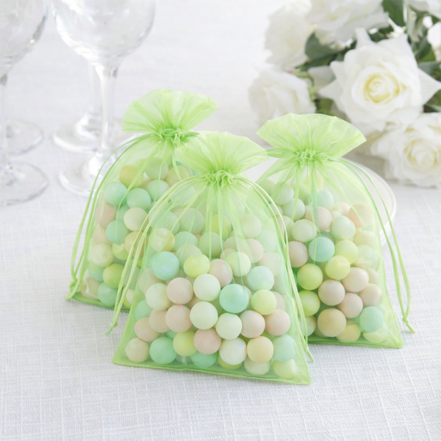 Mint organza gift bags filled with colorful candies, ideal for wedding favors.