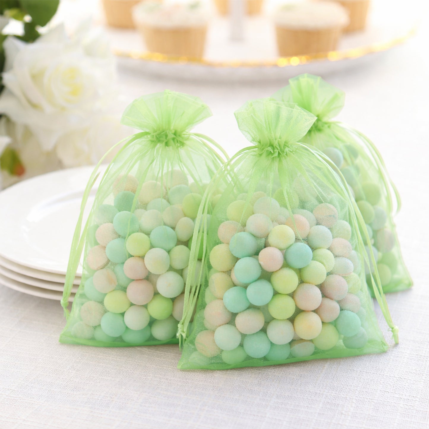 Mint organza gift bags filled with colorful treats, perfect for parties.