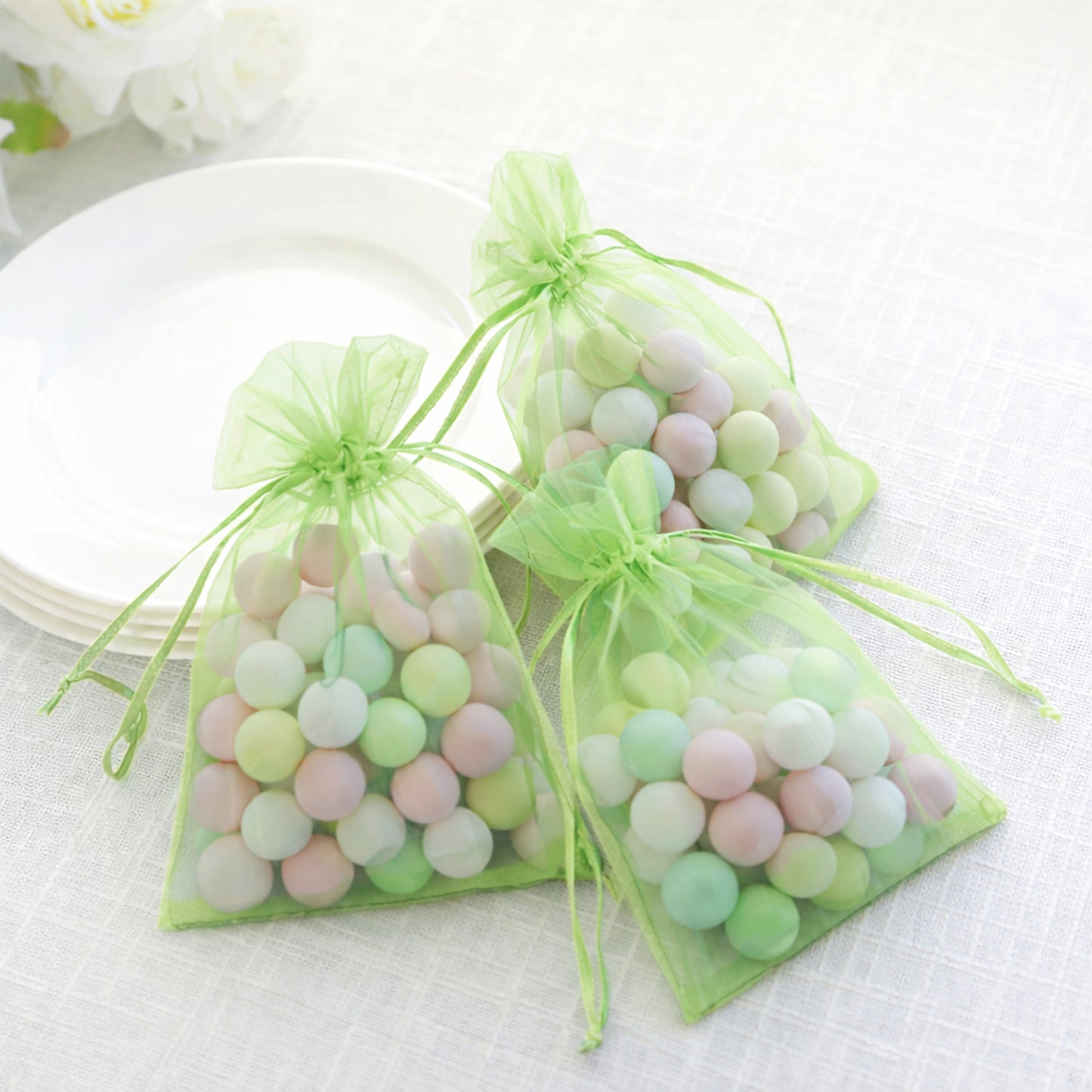 Mint organza gift bags filled with pastel candies, perfect for wedding favors.
