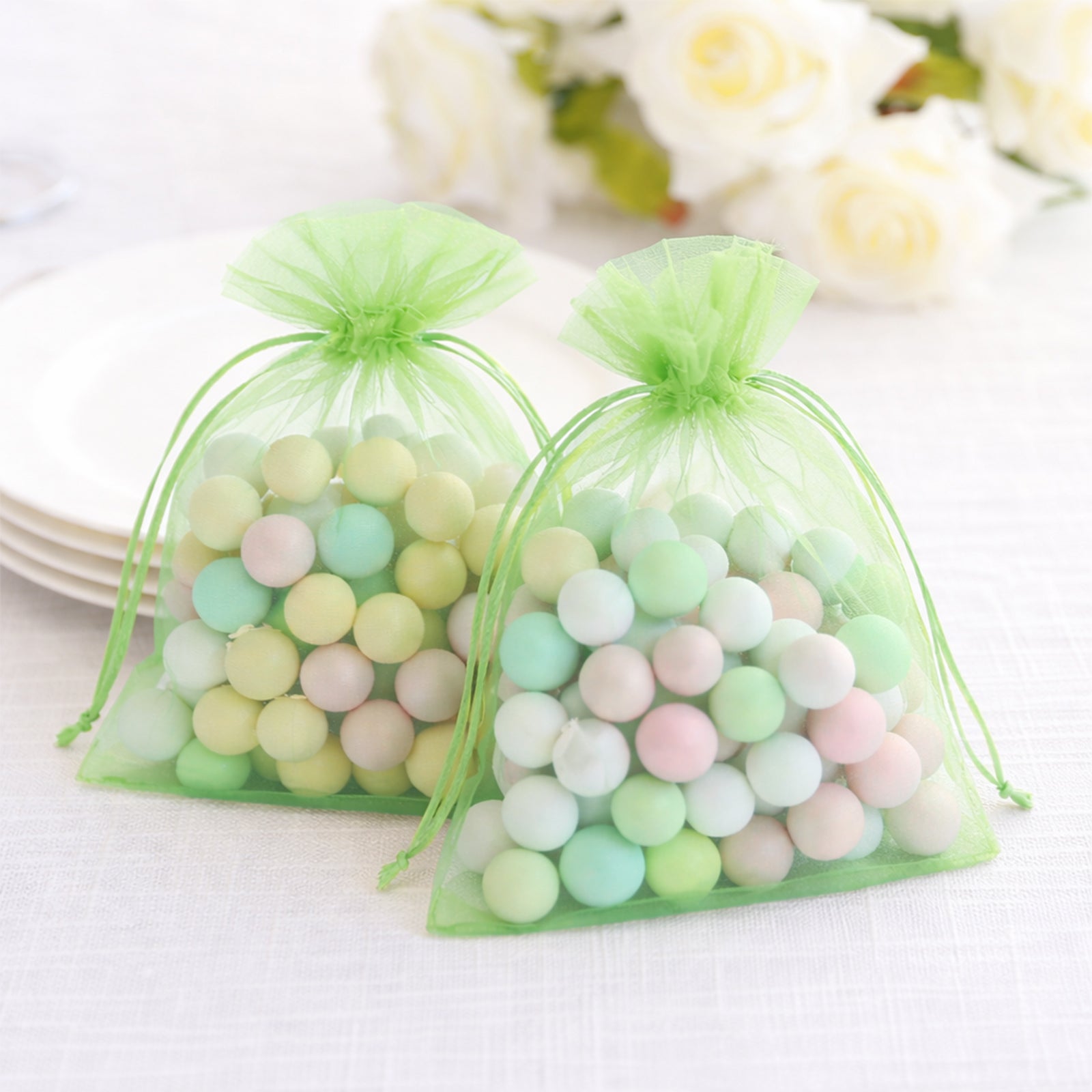 Mint organza gift bags filled with pastel candies, perfect for wedding favors.