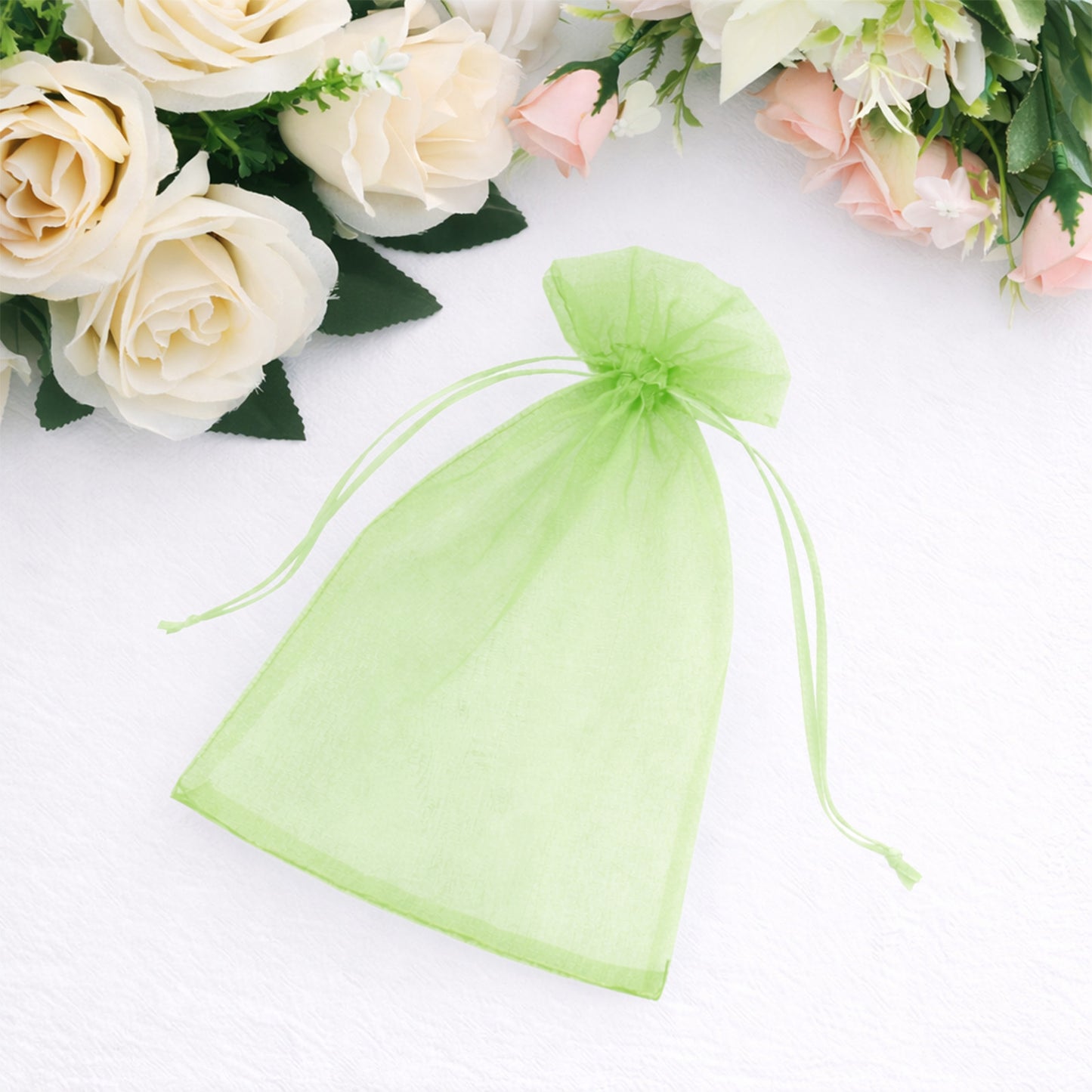 Mint organza gift bag with drawstring among floral decorations.