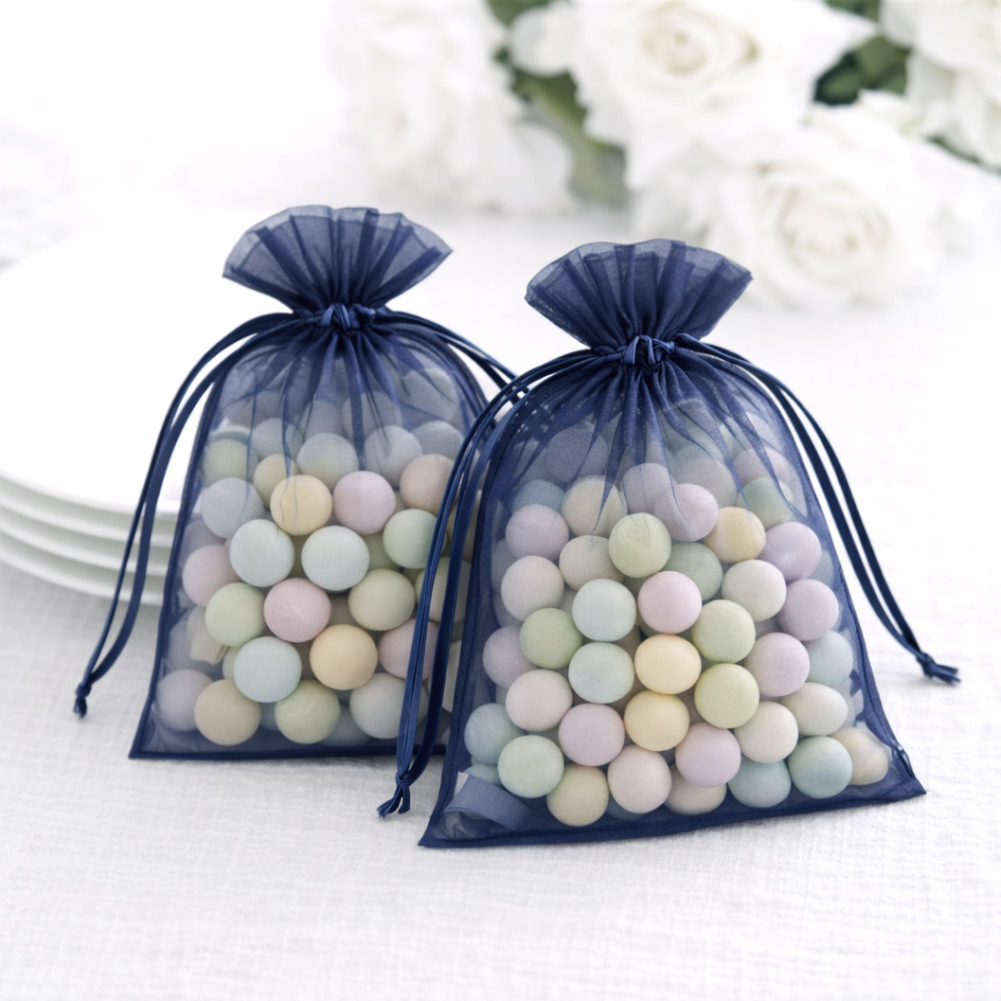Navy blue organza gift bags filled with pastel candies, perfect for wedding favors.
