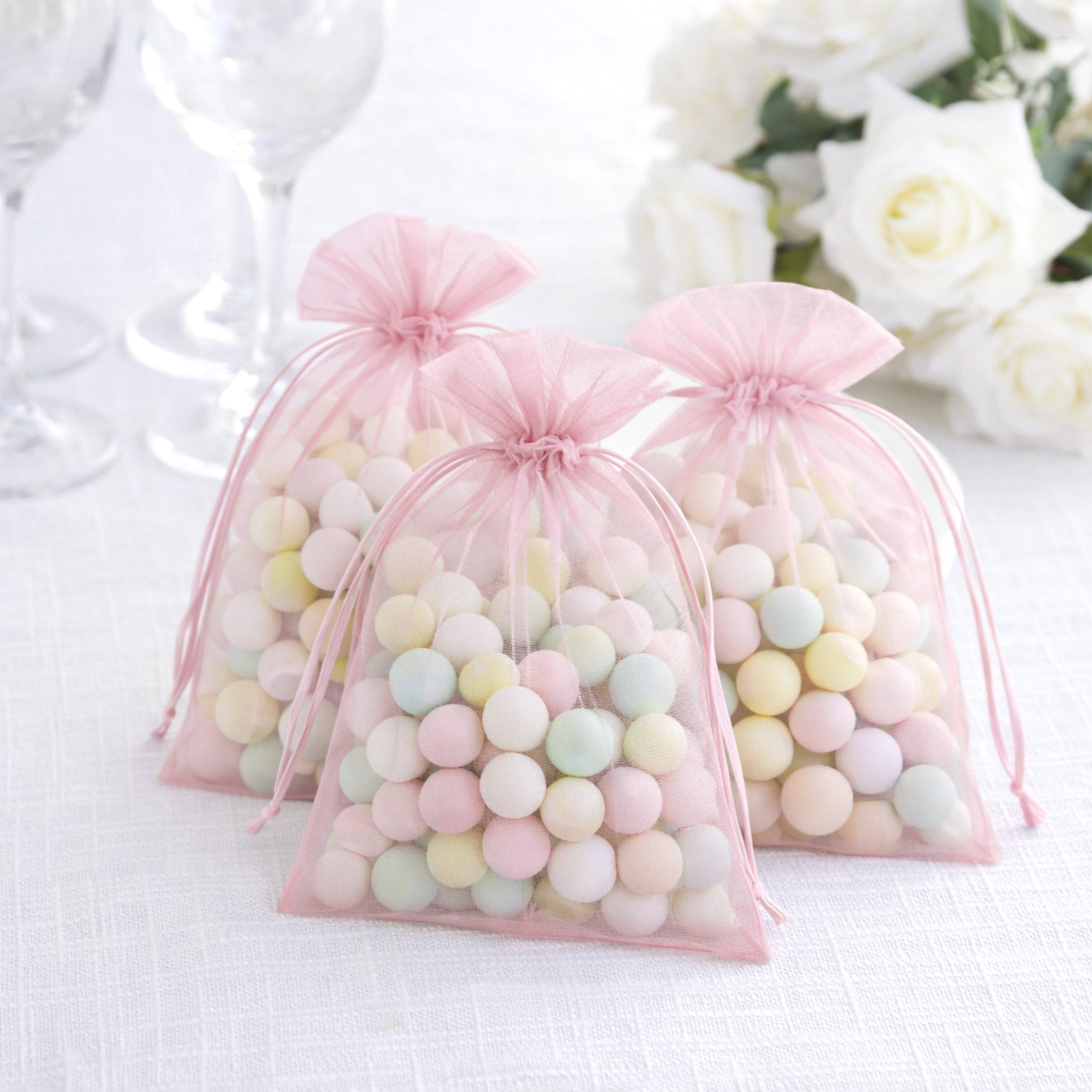 Pink organza gift bags filled with colorful candies. Perfect for weddings.