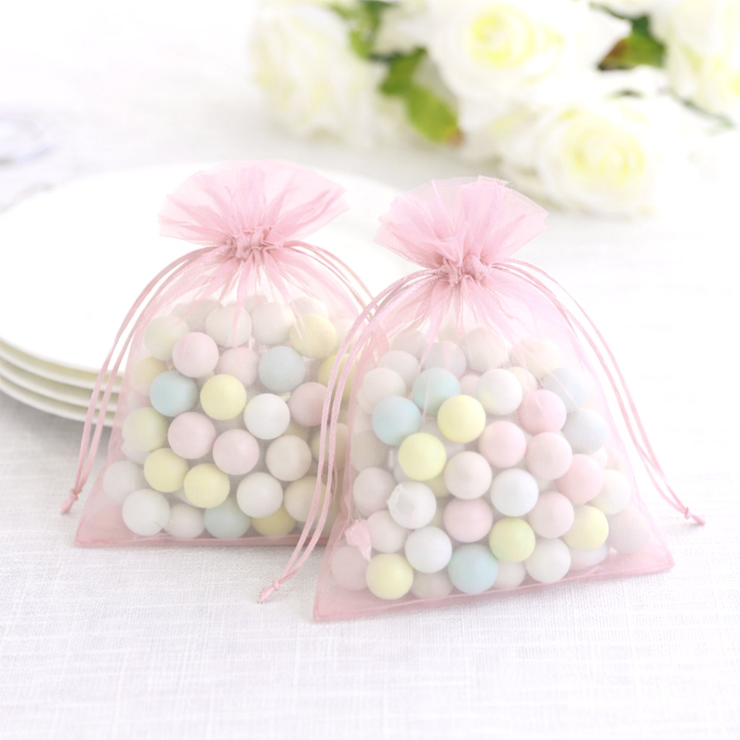 Pink organza gift bags with drawstring, filled with colorful candies.