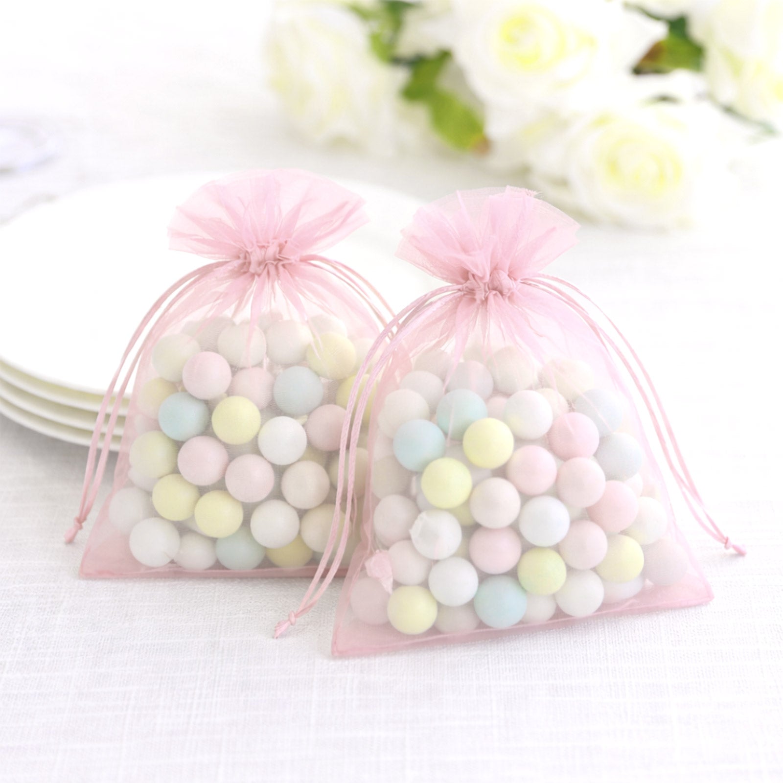 Pink organza gift bags with drawstring, filled with colorful candies.