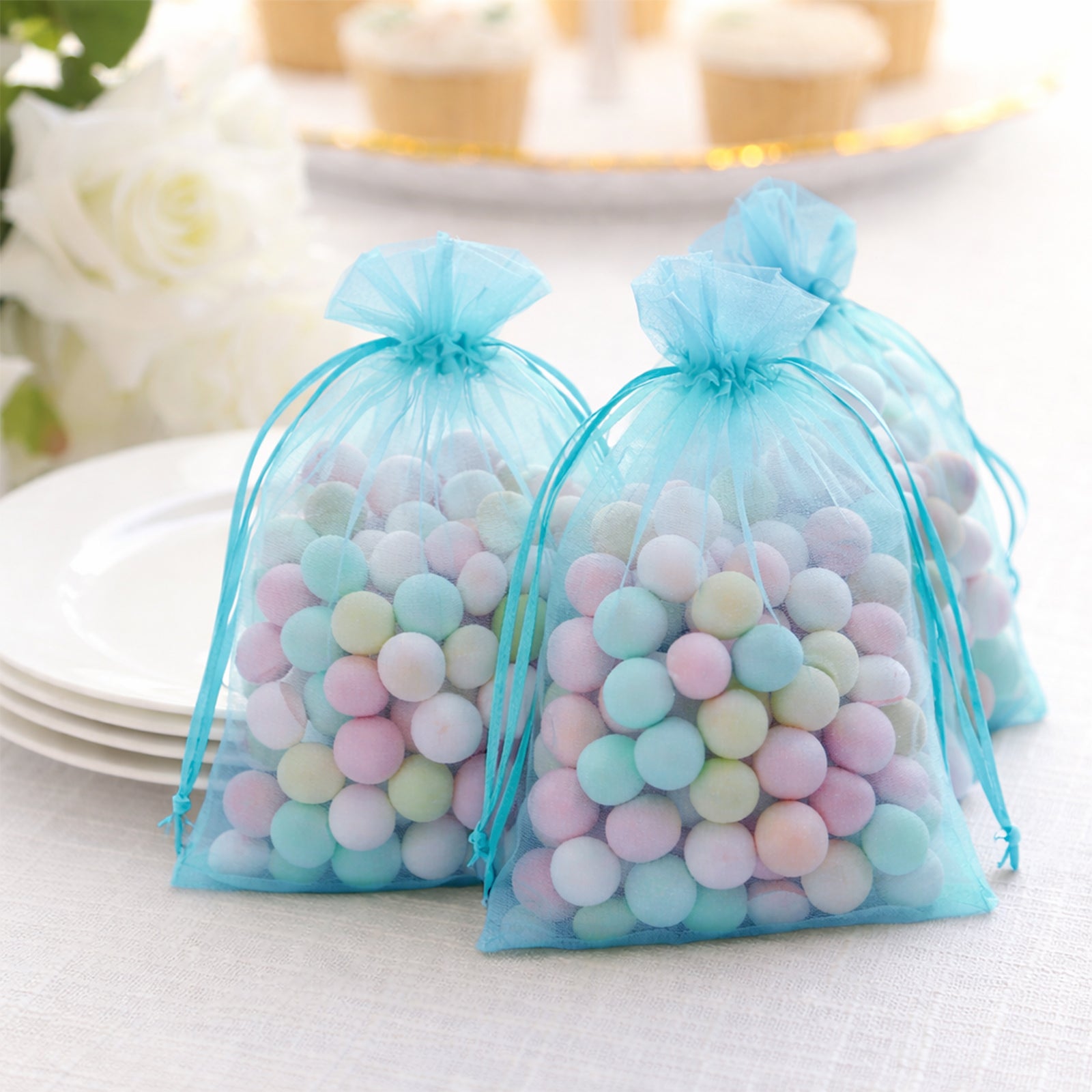 Turquoise organza gift bags filled with colorful candies.
