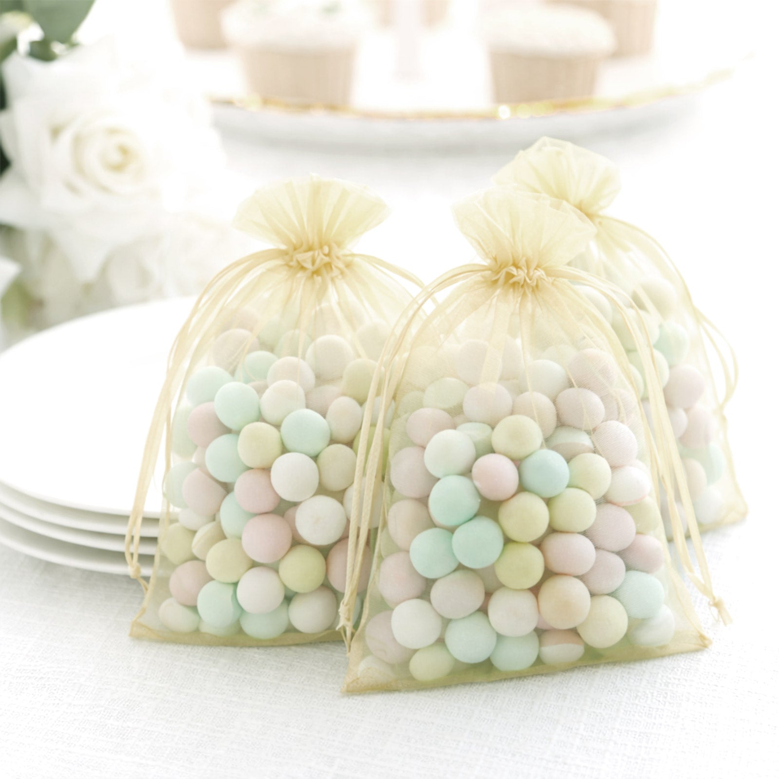 Yellow organza gift bags with drawstring filled with pastel candies.