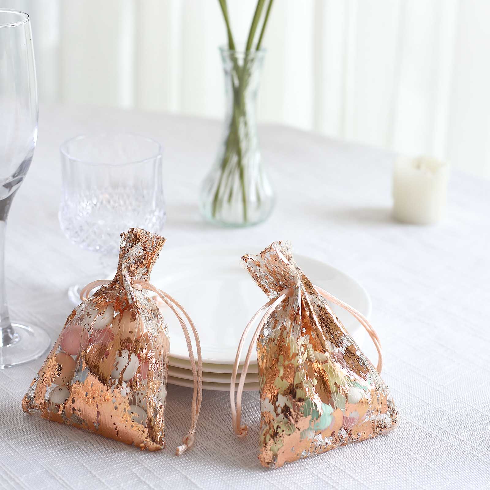 Metallic rose gold foil drawstring candy bags on a dining table.