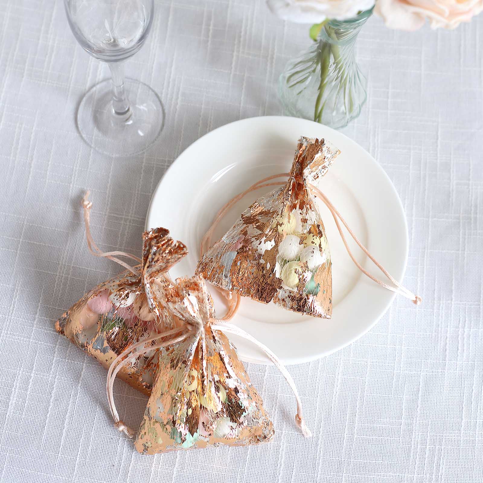 Metallic rose gold drawstring candy bags on a plate.