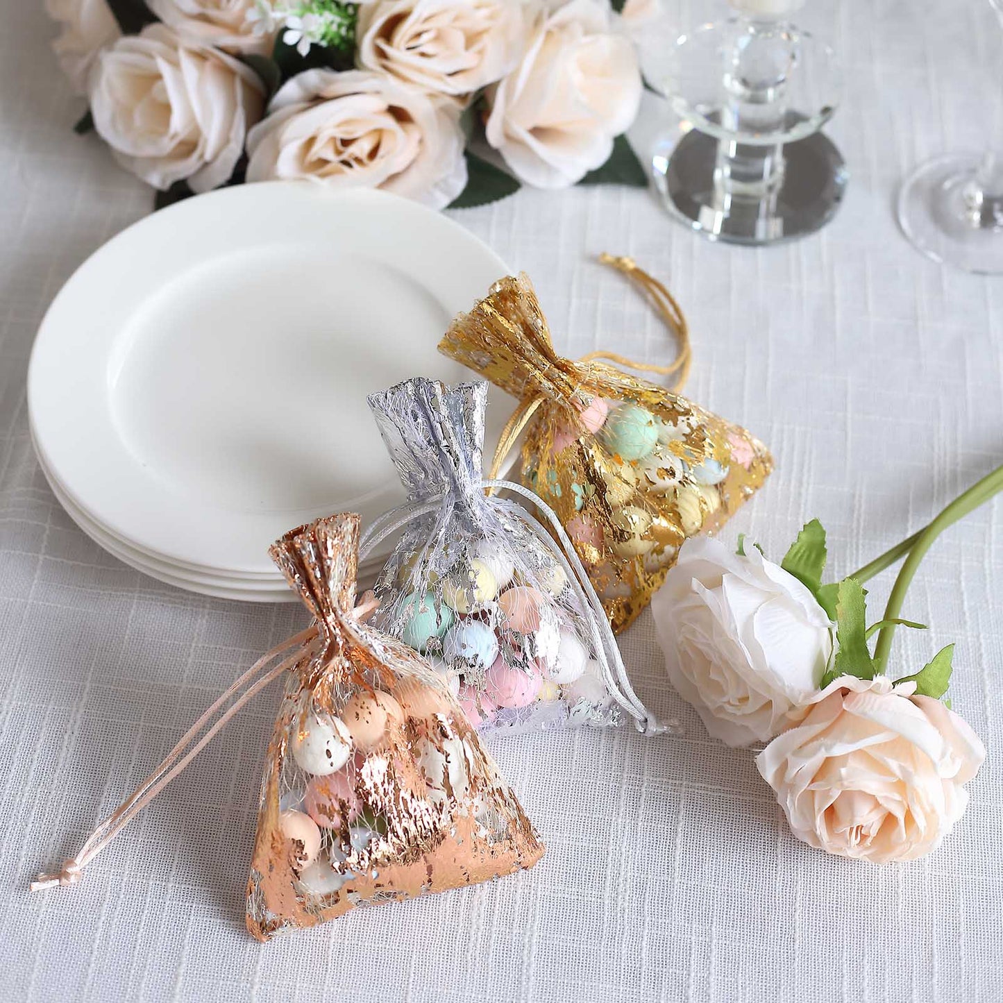 Metallic rose gold foil drawstring candy bags on a table setting.
