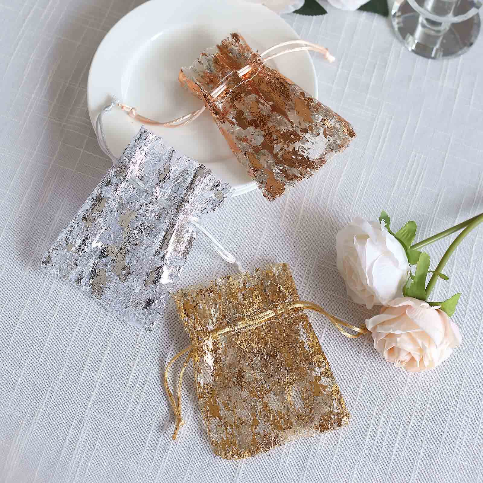 Metallic rose gold and silver drawstring candy bags on a plate.