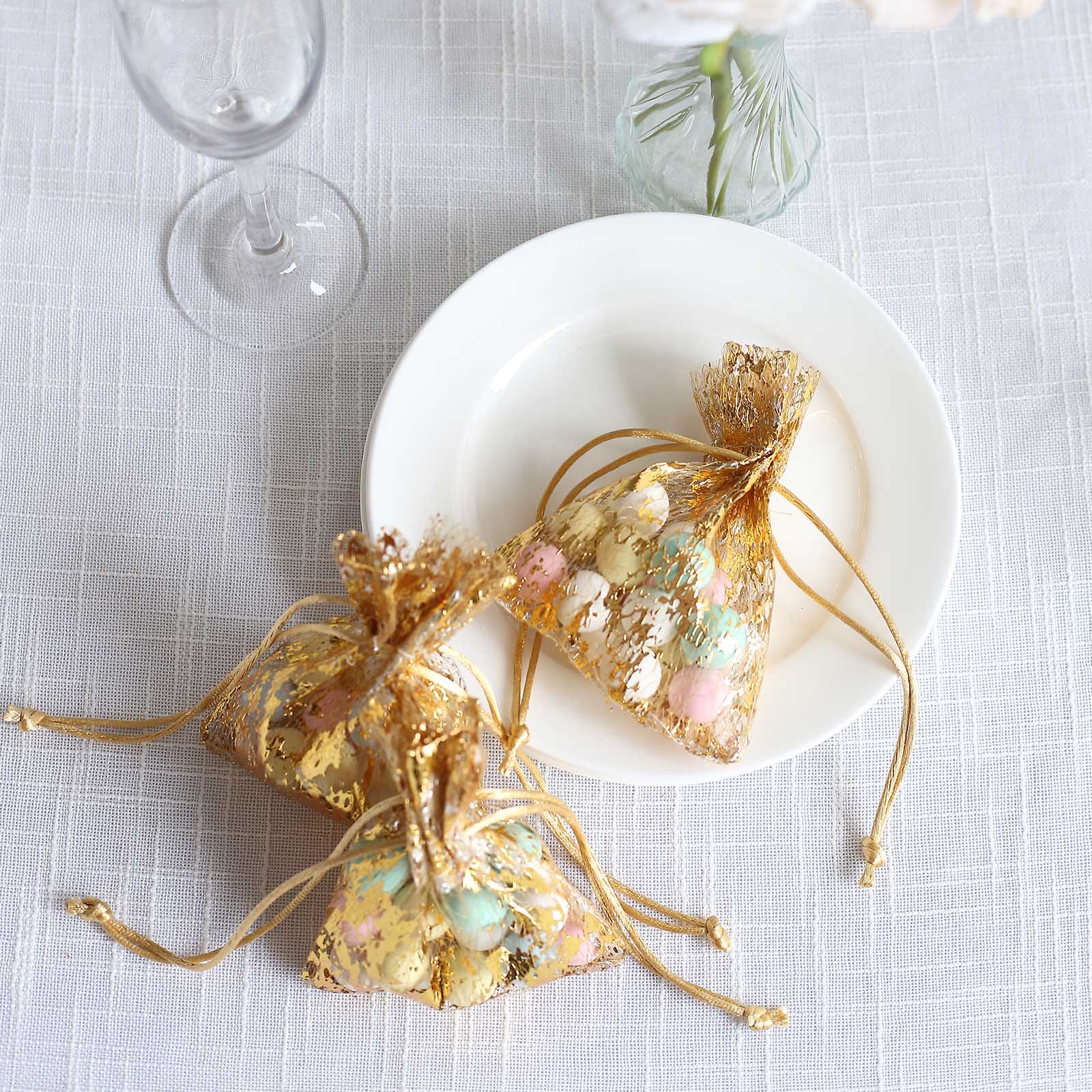 Metallic gold drawstring candy bags on a plate, ideal for wedding favors.