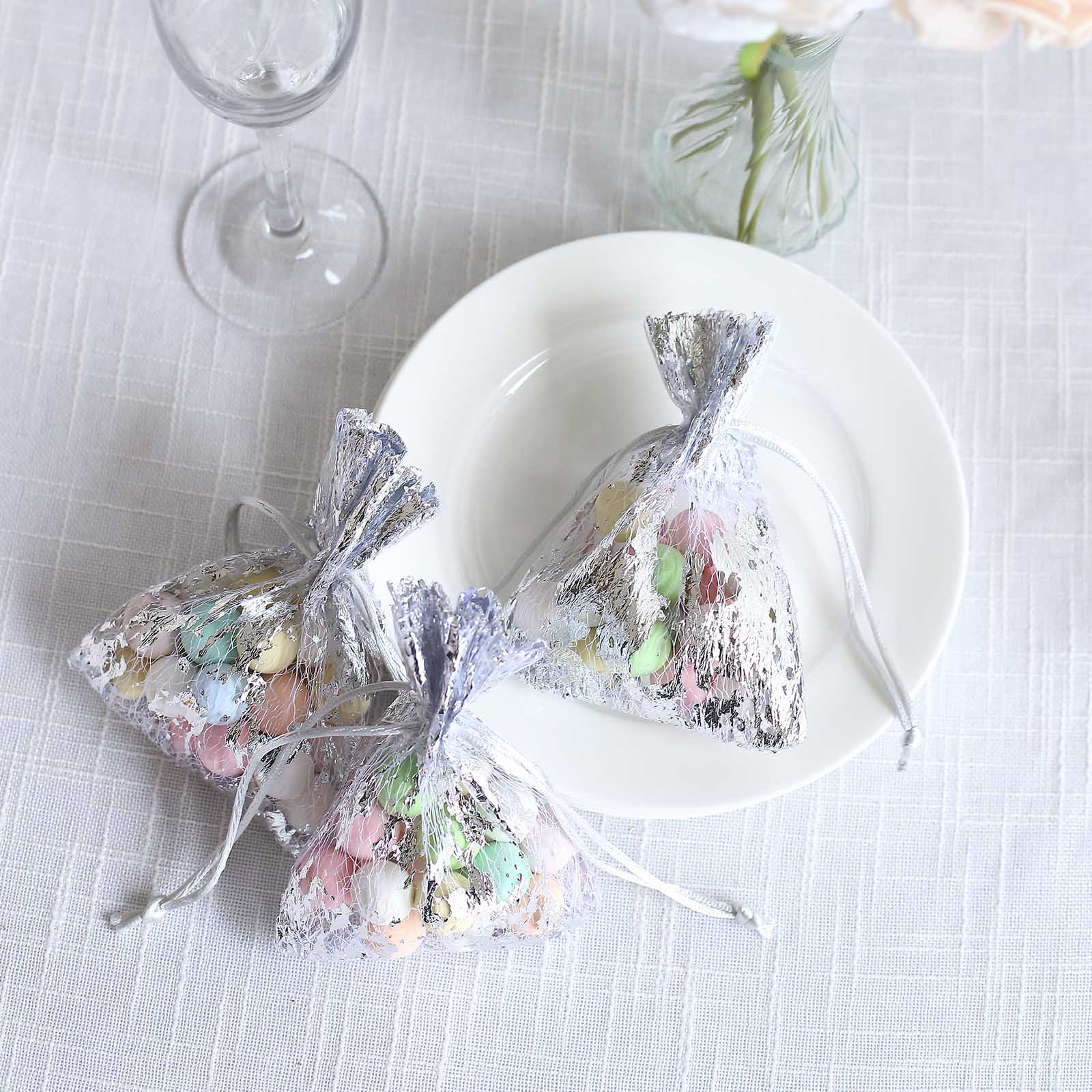 Metallic silver foil drawstring candy bags filled with pastel candies.