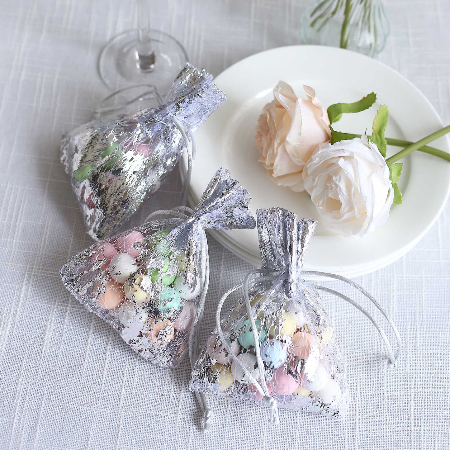 Metallic silver foil drawstring candy bags with pastel candies.