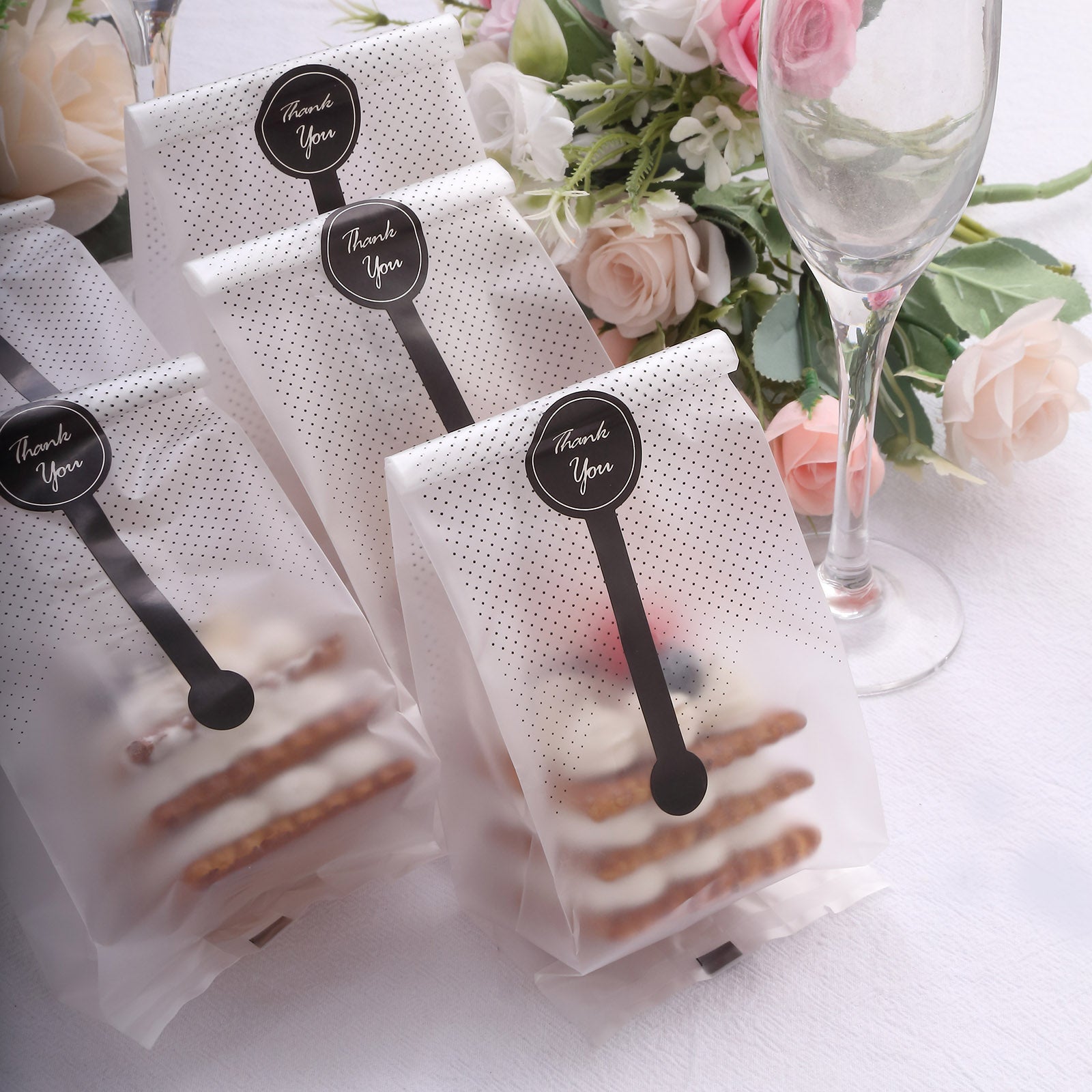 Clear black dotted gift bags with "Thank You" stickers on a table.