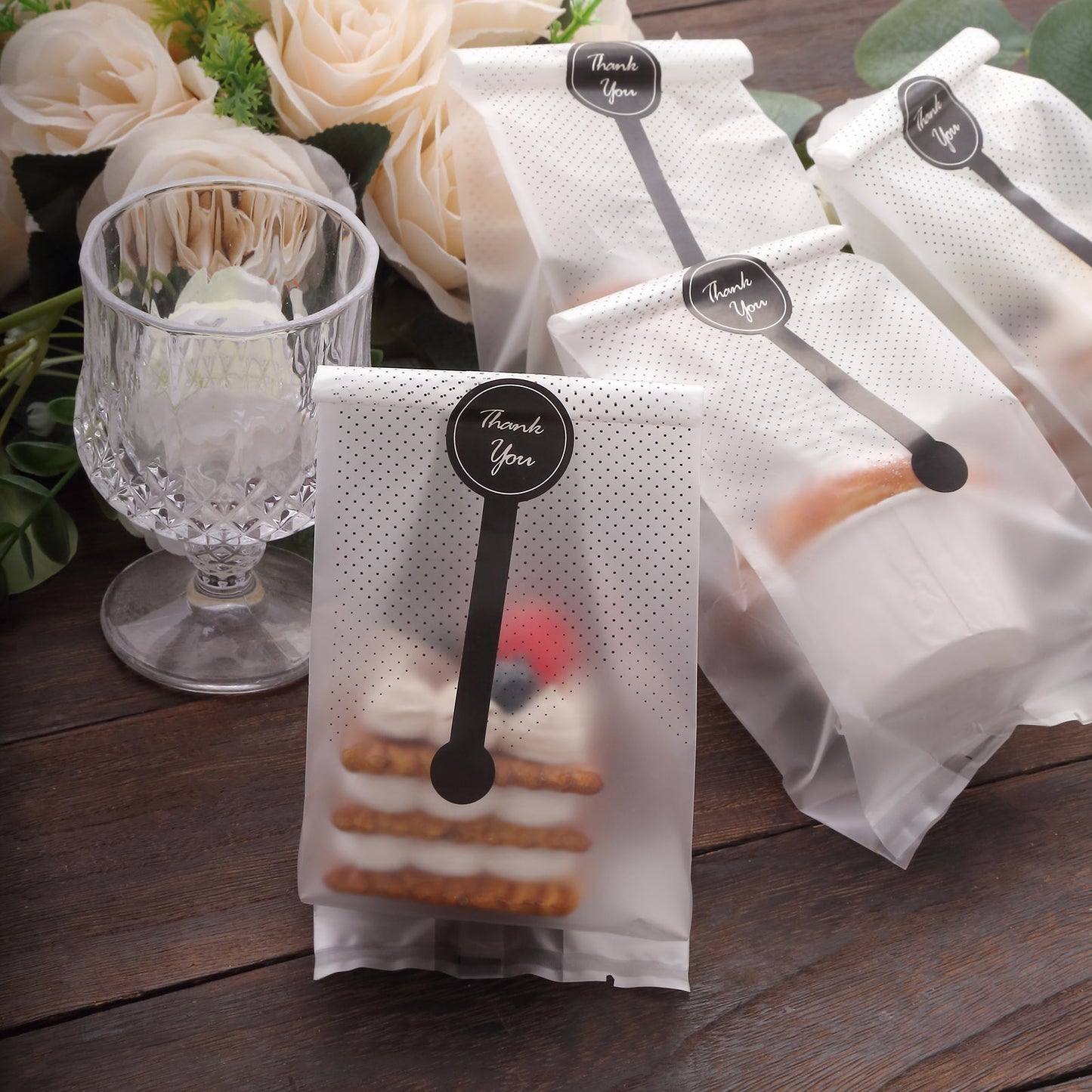 Clear black dotted gift bags with "Thank You" stickers for party favors.