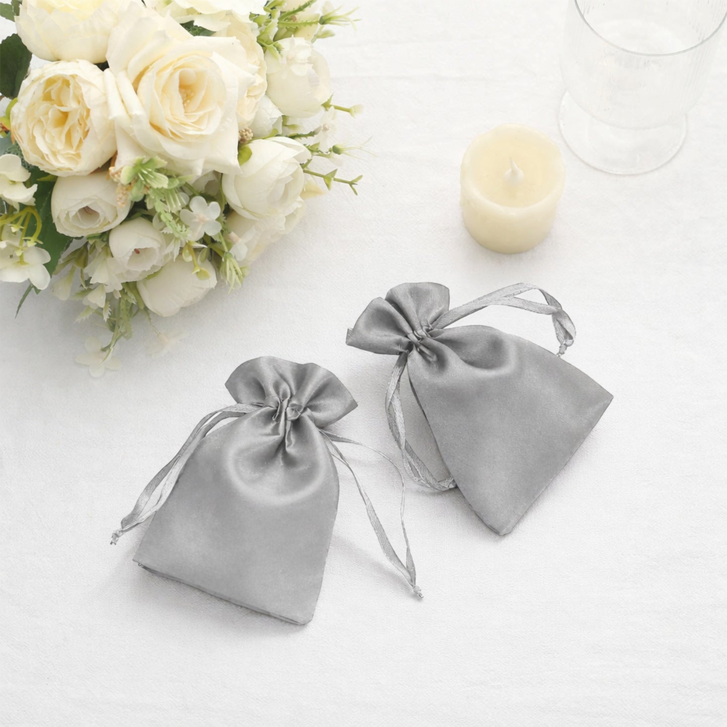 Silver satin drawstring favor bags for weddings and parties.