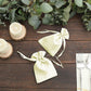 Yellow satin drawstring favor bags on a rustic table with greenery.