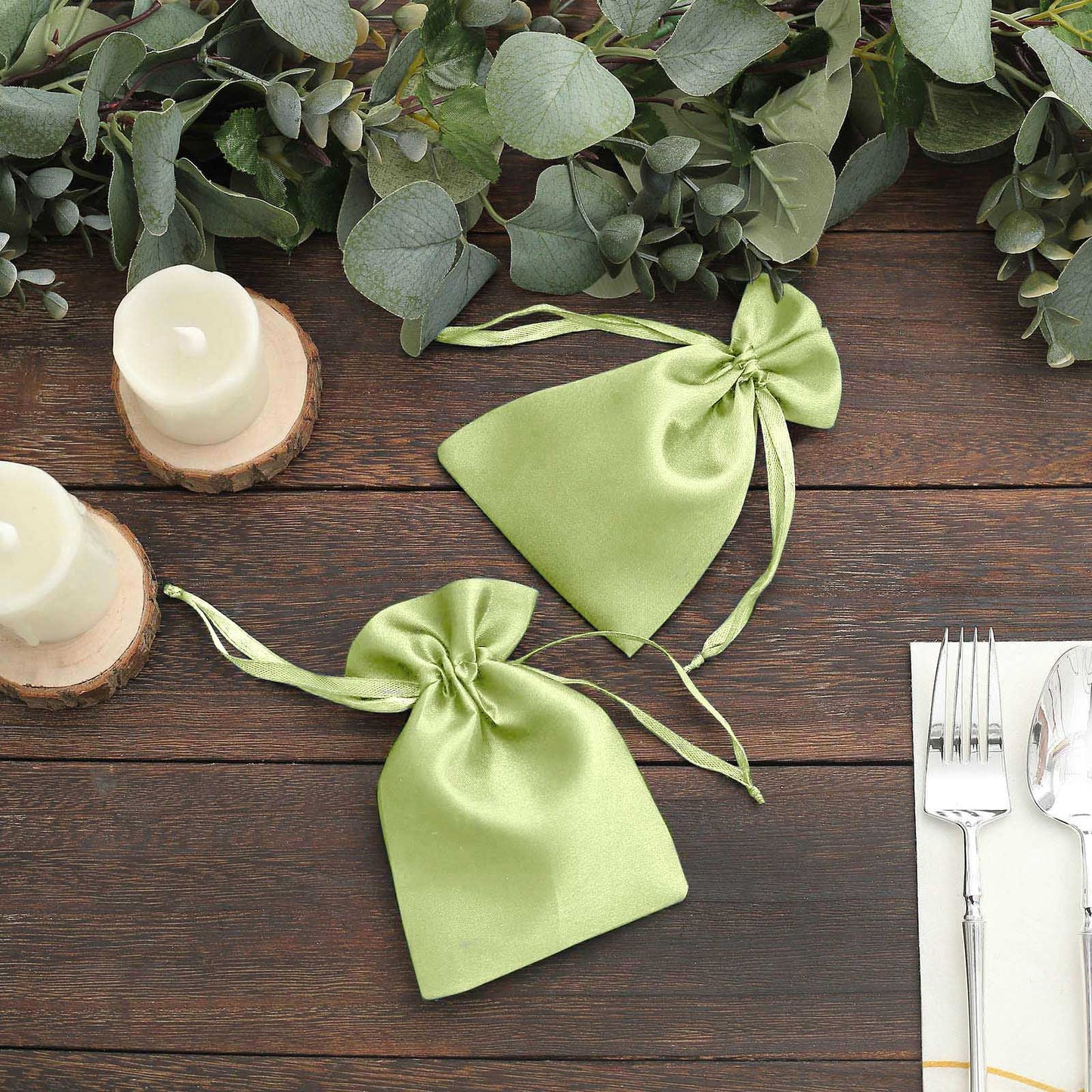 Apple green satin drawstring pouch gift bags on a rustic table setting.