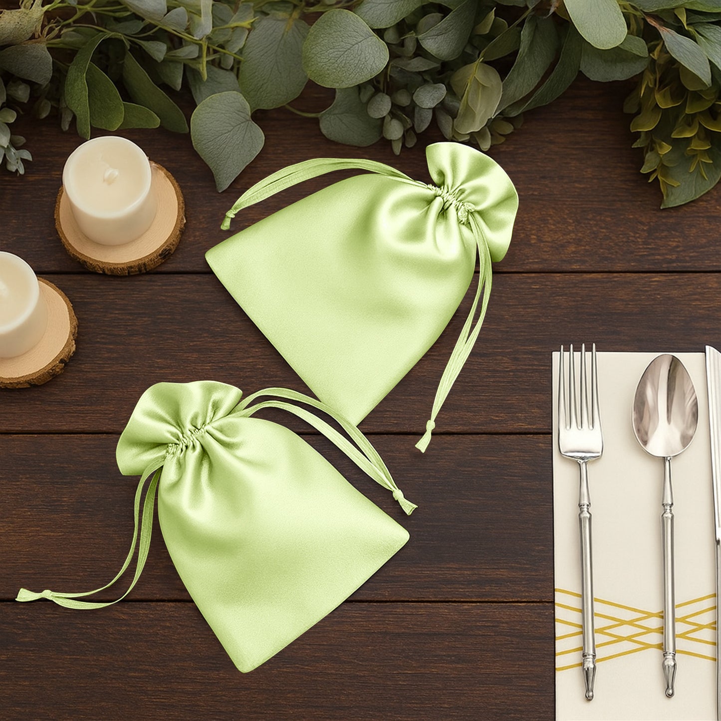 Apple green satin drawstring gift bags on a wooden table with candles and utensils.