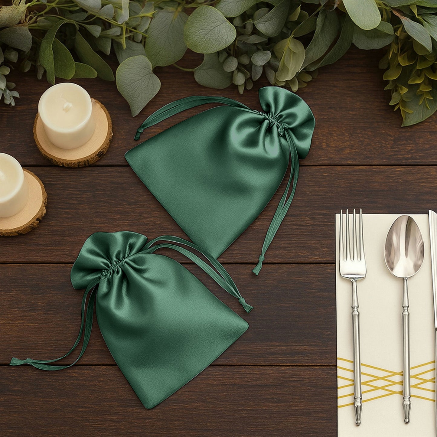 Hunter emerald green satin drawstring wedding favor bags on a wooden table.